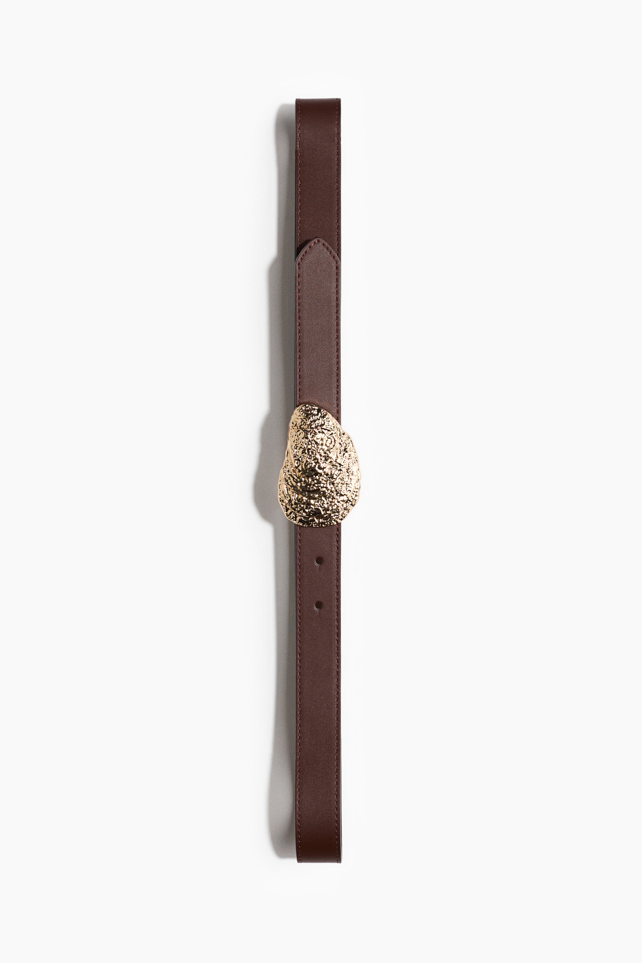 View larger image: A dark brown leather belt is laid out flat, showcasing an irregularly shaped, textured gold-toned buckle at its center. The belt strap includes multiple adjustment holes and a matching brown leather keeper.