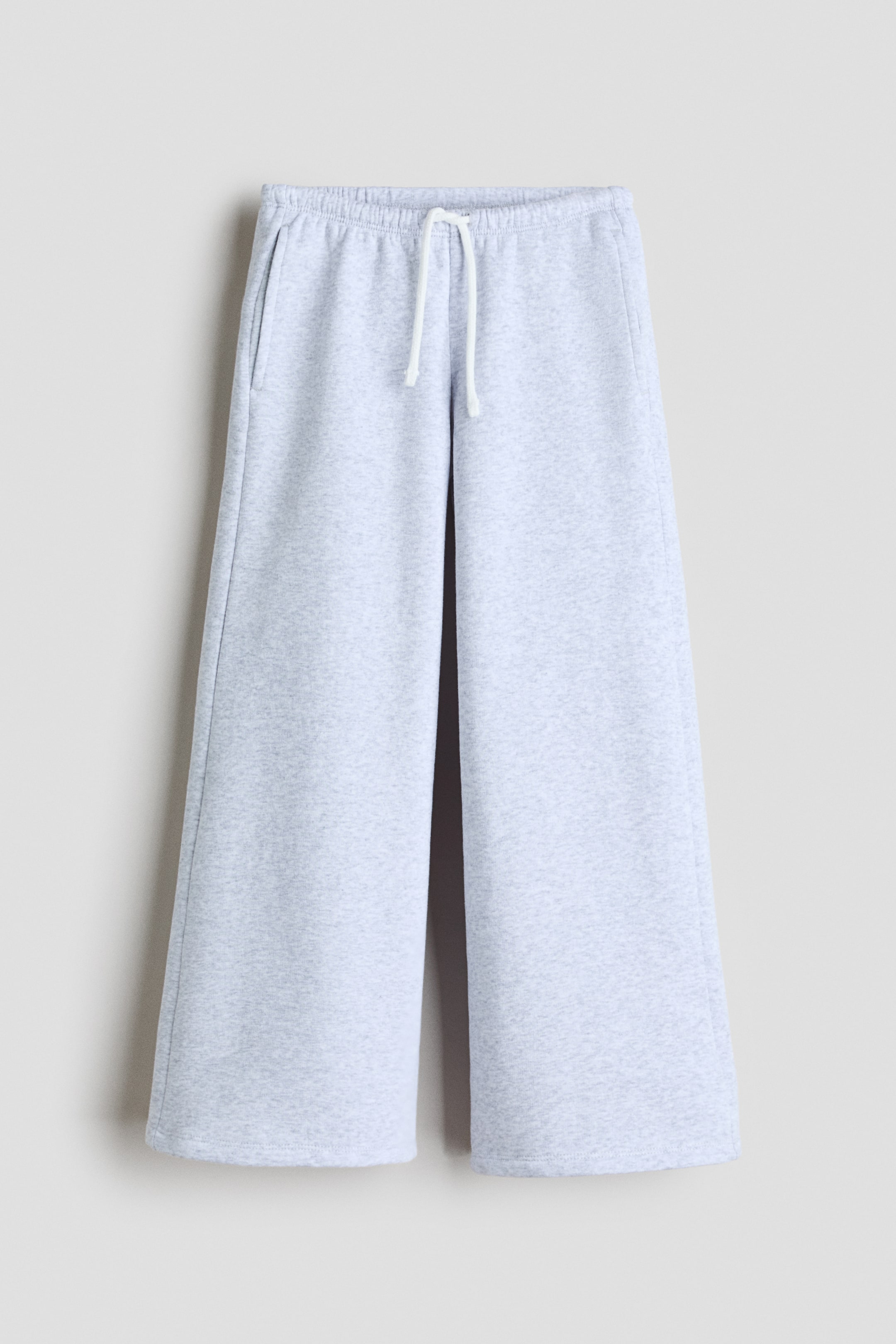 View larger image: The light gray marl sweatpants are shown from the front, featuring an elastic waistband with a white drawstring, visible side pockets, and wide, straight legs with plain hems.