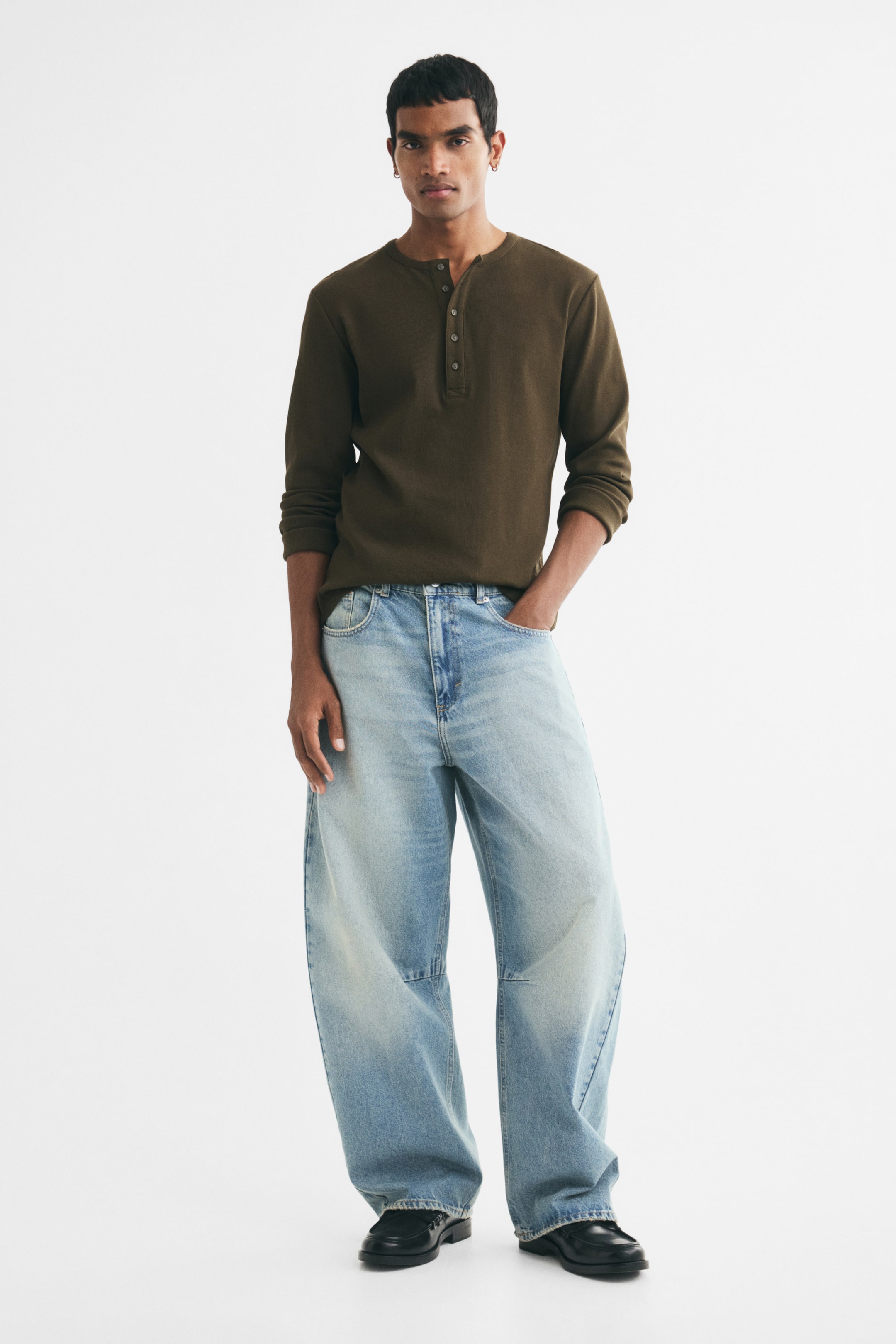 View larger image: Light blue 5-pocket jeans in rigid cotton denim, featuring a regular waist and zip fly, are worn by the model. The jeans have barrel legs with a baggy fit, providing ample room from the seat to the hem, and the model is standing with one hand in a front pocket.