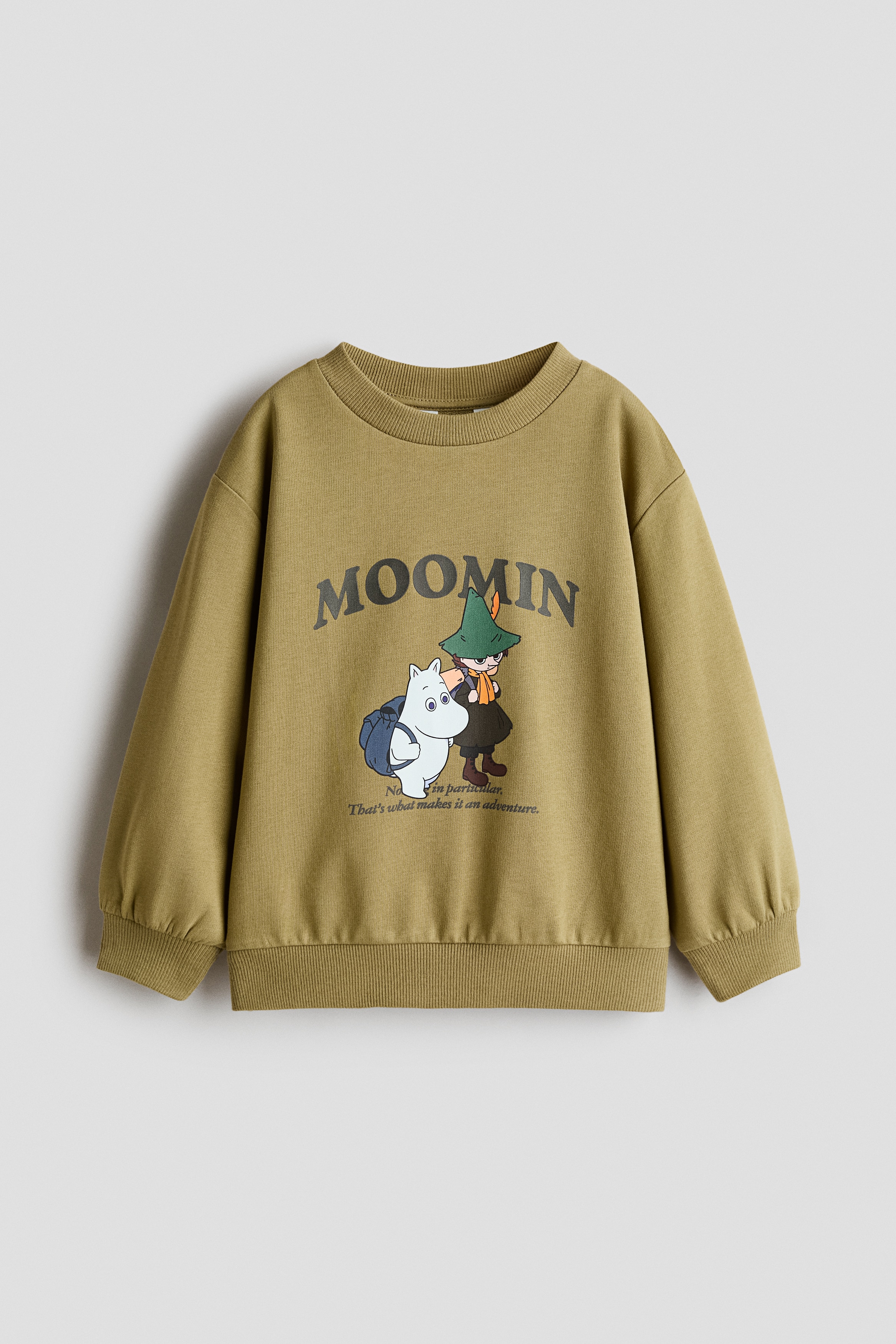 æ¨¡ç¹åæ­£åèç©¿èä¸ä»¶ç¶ è²è¼èè¡è¡£ï¼æ­£é¢å°æ Moomin åæ¡ãéä»¶ä¸è¡£æ¡ç¨ç¾ç´åé è¨­è¨èè½è©åªè£ï¼ä¸¦æ­éèè²çä»è¤²åéåéã