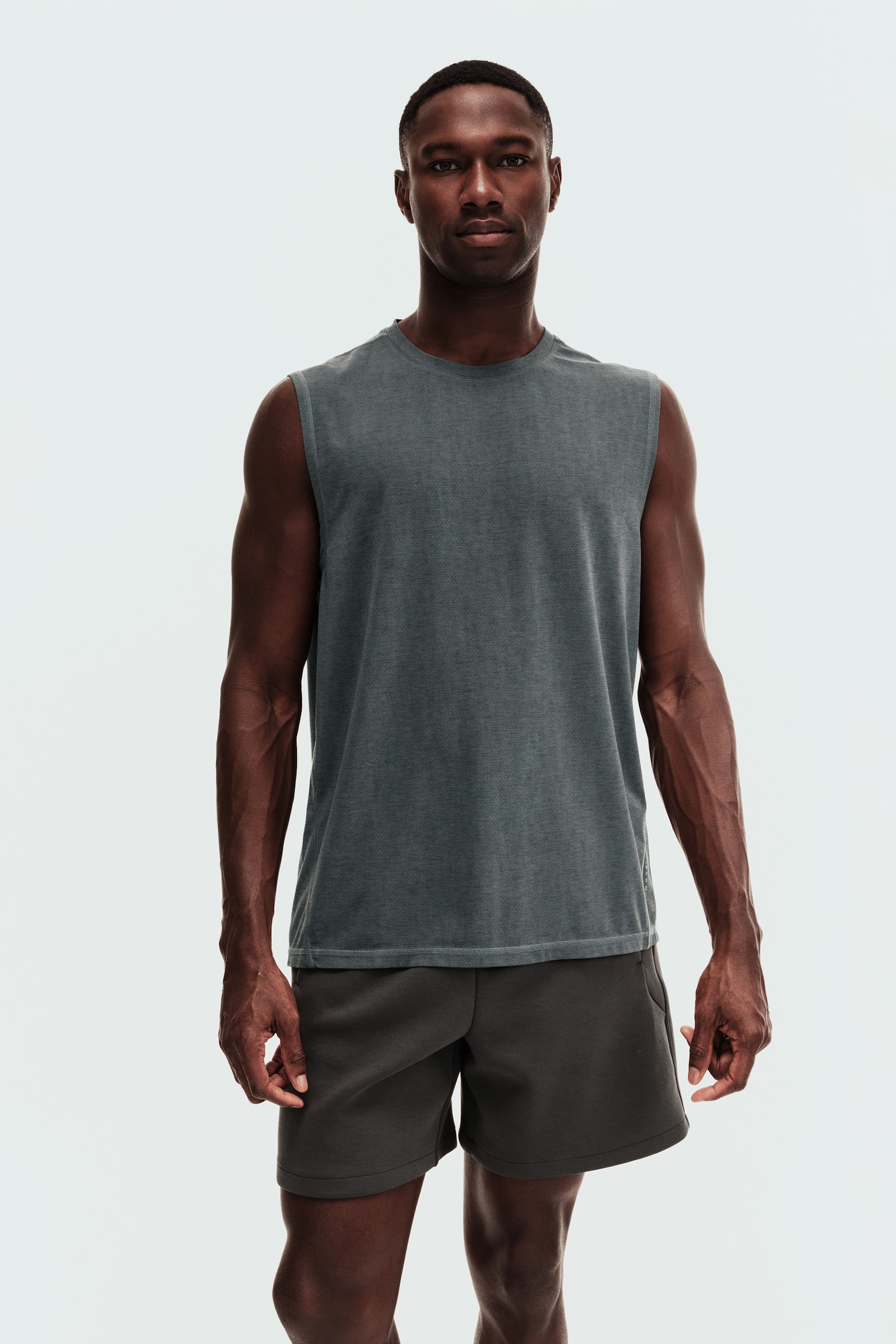 A dark grey regular fit sports vest top with DryMove?, featuring a crew neck and sleeveless design, is being worn by the model. The model is also wearing dark grey shorts. - 1
