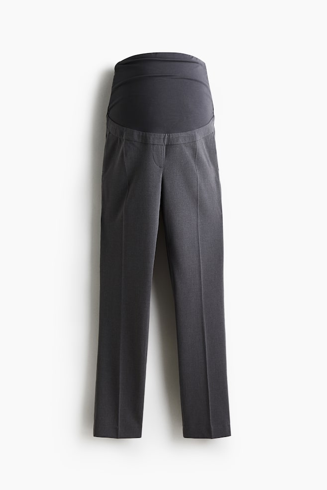Dark gray maternity pants are shown from the front, featuring a wide, integrated over-the-belly panel in a matching dark gray fabric. The straight-leg trousers are displaying a prominent crease running down the front of each leg. - 1