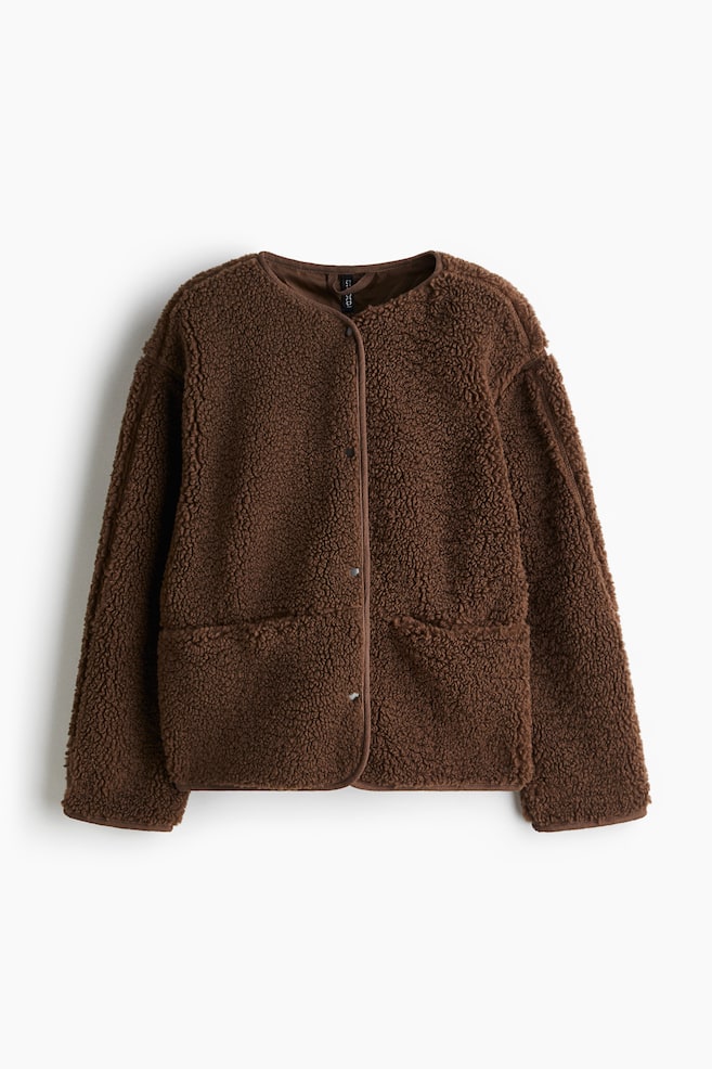 Une veste en peluche marron est présentée de FACE, avec un bord en jersey le long de ses contours, des boutons-pression sombres au centre devant, des épaules tombantes et des poches avant discrètes avec des fermetures à boutons-pression dissimulées. - 1