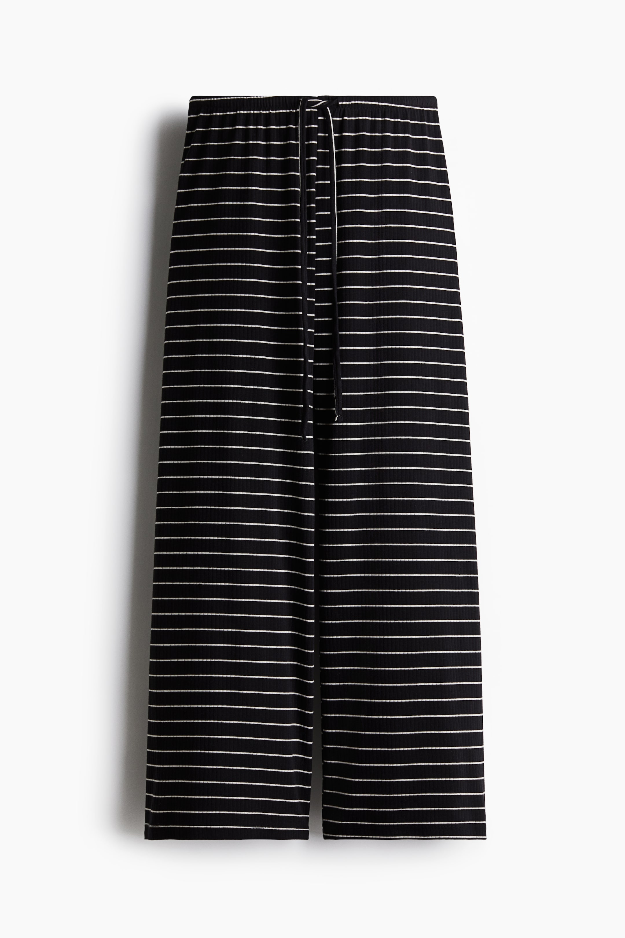 Vezi imaginea mai mare: Pantalonii prezintă un material negru cu dungi subțiri orizontale albe și o textură în relief. Aceștia sunt echipați cu o talie elastică cu șnur alb și au un stil cu cracul larg.