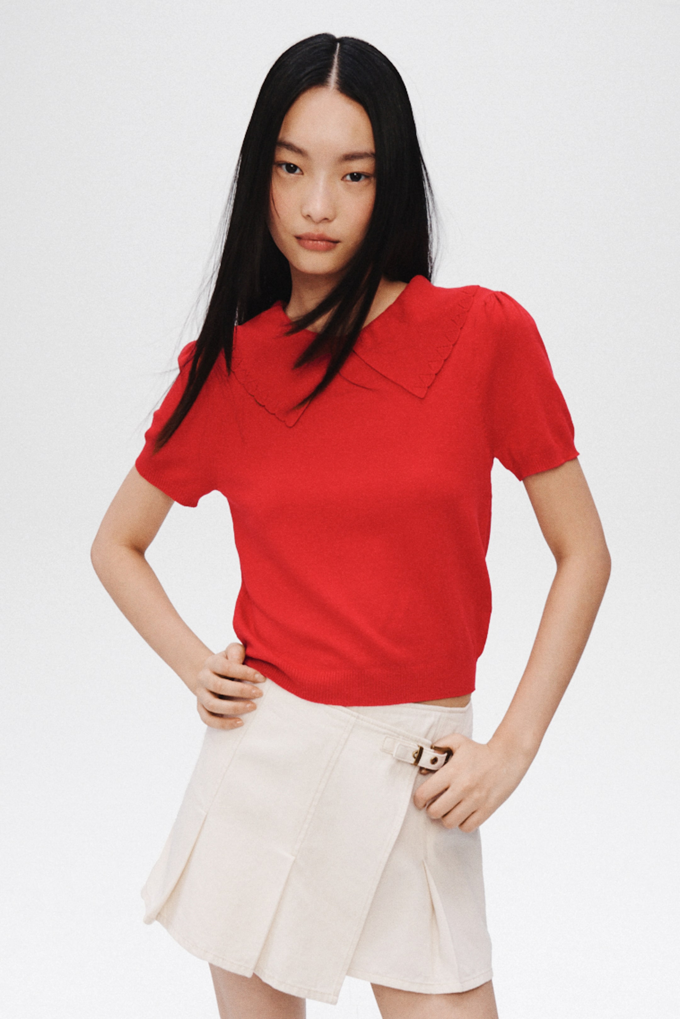 View larger image: A red short-sleeved knit top featuring a wide, pointed collar with a scalloped, open-work edge, short puffed sleeves, and a ribbed hem.