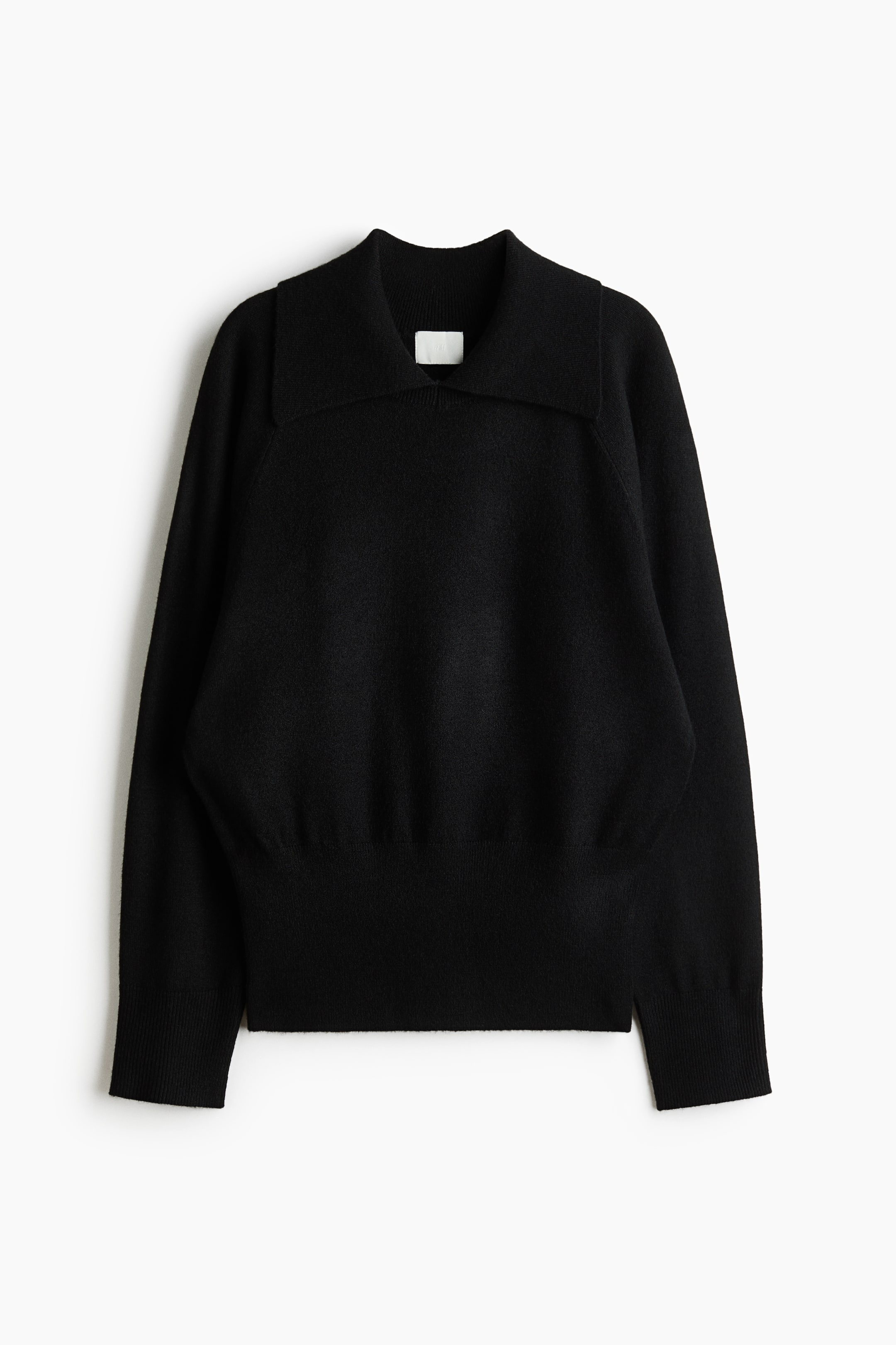 Agrandir l'image: Un pull en maille noir est présenté de face, avec un large col à revers, un col en V peu profond, des manches longues avec poignets côtelés et un large ourlet côtelé.