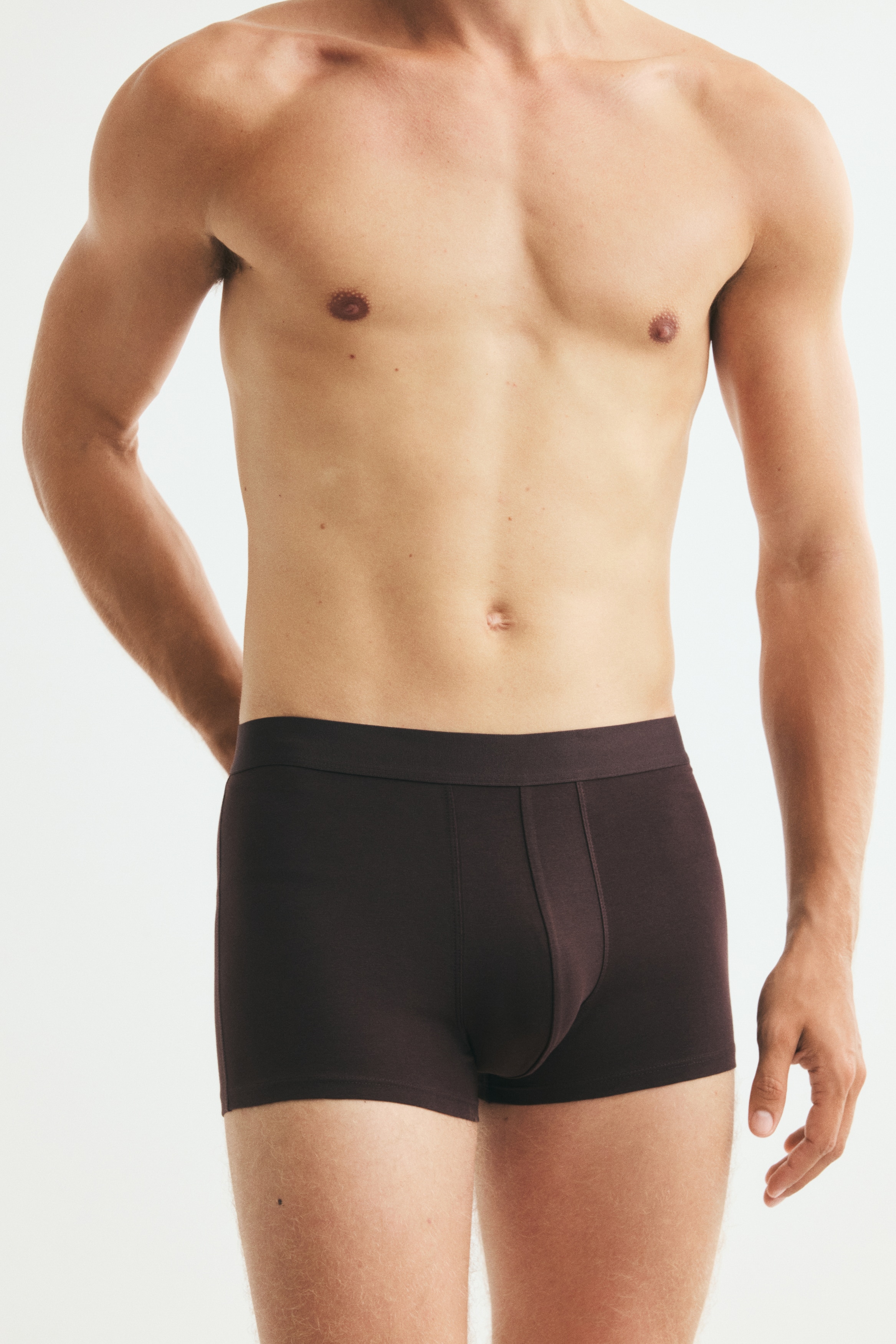 Fünf Paar Herren-Boxershorts sind gestapelt und zeigen verschiedene Brauntöne und Schwarz. Jede Boxershorts verfügt über einen elastischen Bund und auffällige Nähte an der Vorderseite.