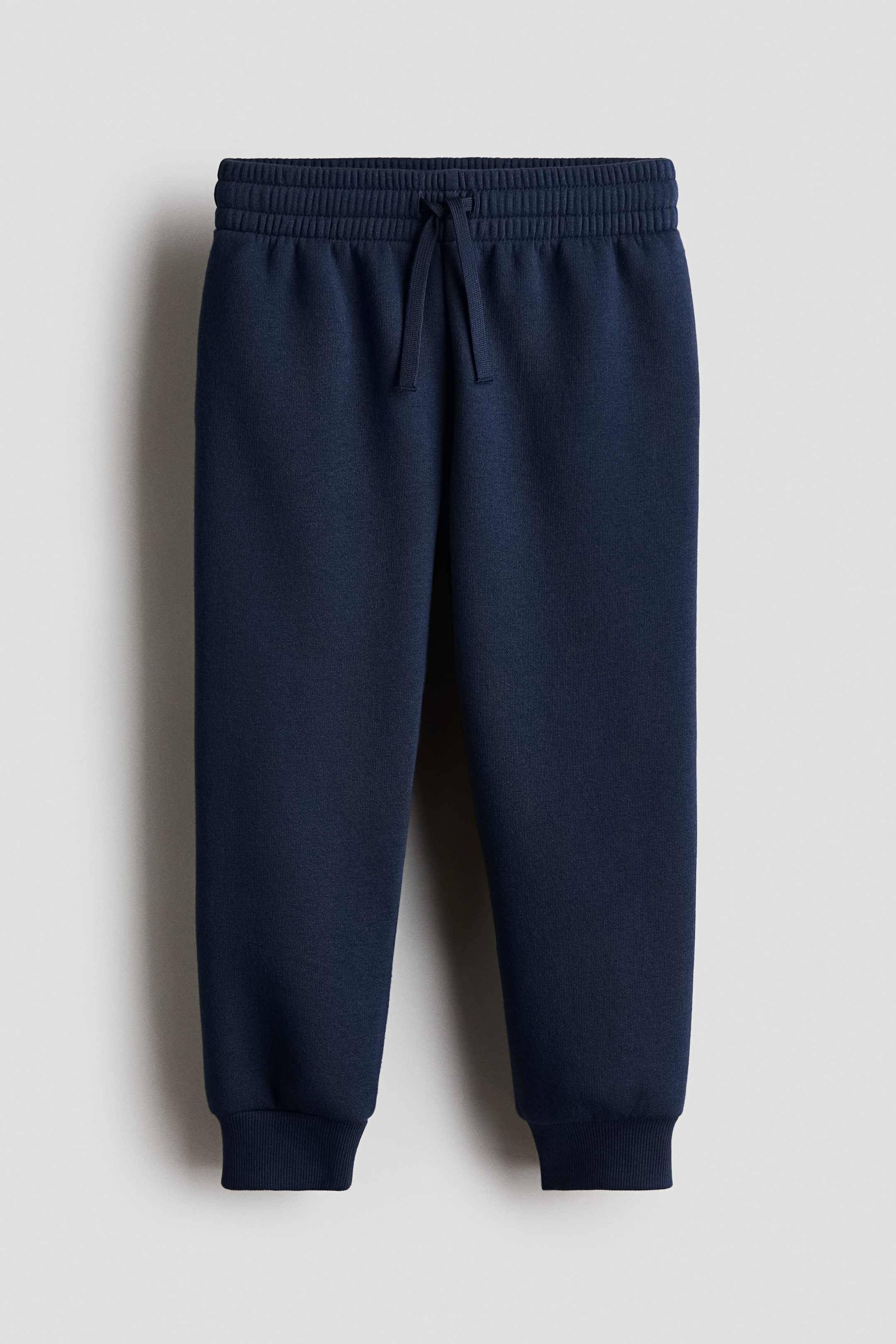 View larger image: Navy blue sweatpants feature an elastic waistband with a front drawstring and ribbed cuffs at the ankles.