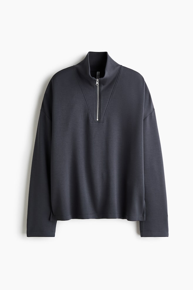 A dark gray half-zip sweatshirt is shown from the front, featuring a high stand-up collar with a silver-tone metal zipper and decorative V-shaped seam details. The pullover is displaying a relaxed silhouette with dropped shoulders, long sleeves with clean-finished cuffs, and a straight hem with small side slits. - 1