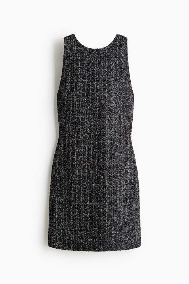 The front of a sleeveless black tweed mini dress is displaying a textured, vertically striped weave with subtle metallic silver flecks. The dress is featuring a round neckline, a fitted waist, and a structured A-line skirt. - 1