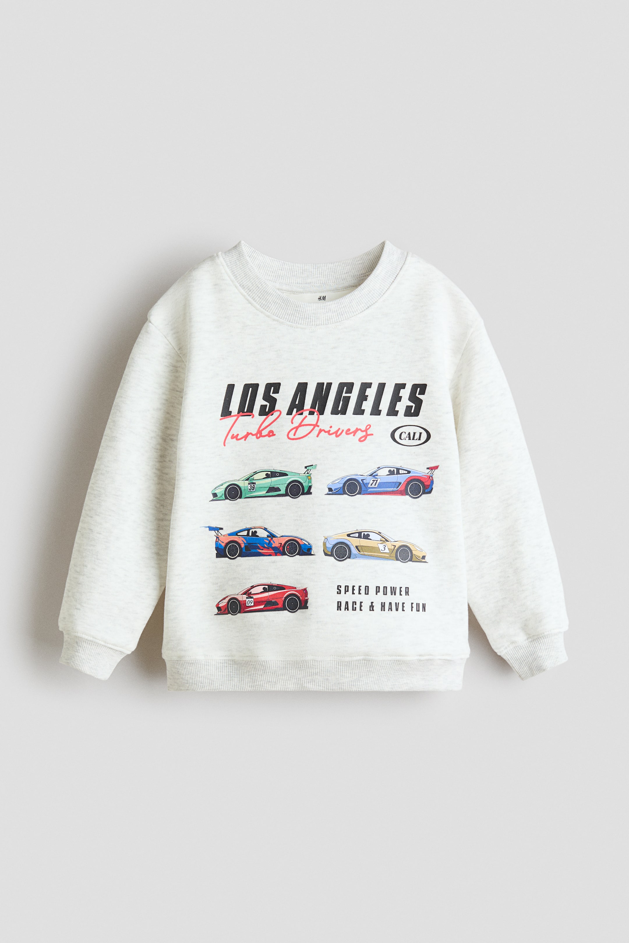 View larger image: A light grey marl sweatshirt, crafted from printed sweatshirt fabric, is showcased FRONT, featuring a round, rib-trimmed neckline, dropped shoulders, long sleeves with ribbed cuffs, and a ribbed hem. The front displays a graphic print with "LOS ANGELES Turbo Drivers CALI" text and six colourful race cars, alongside "SPEED POWER RACE & HAVE FUN" text.