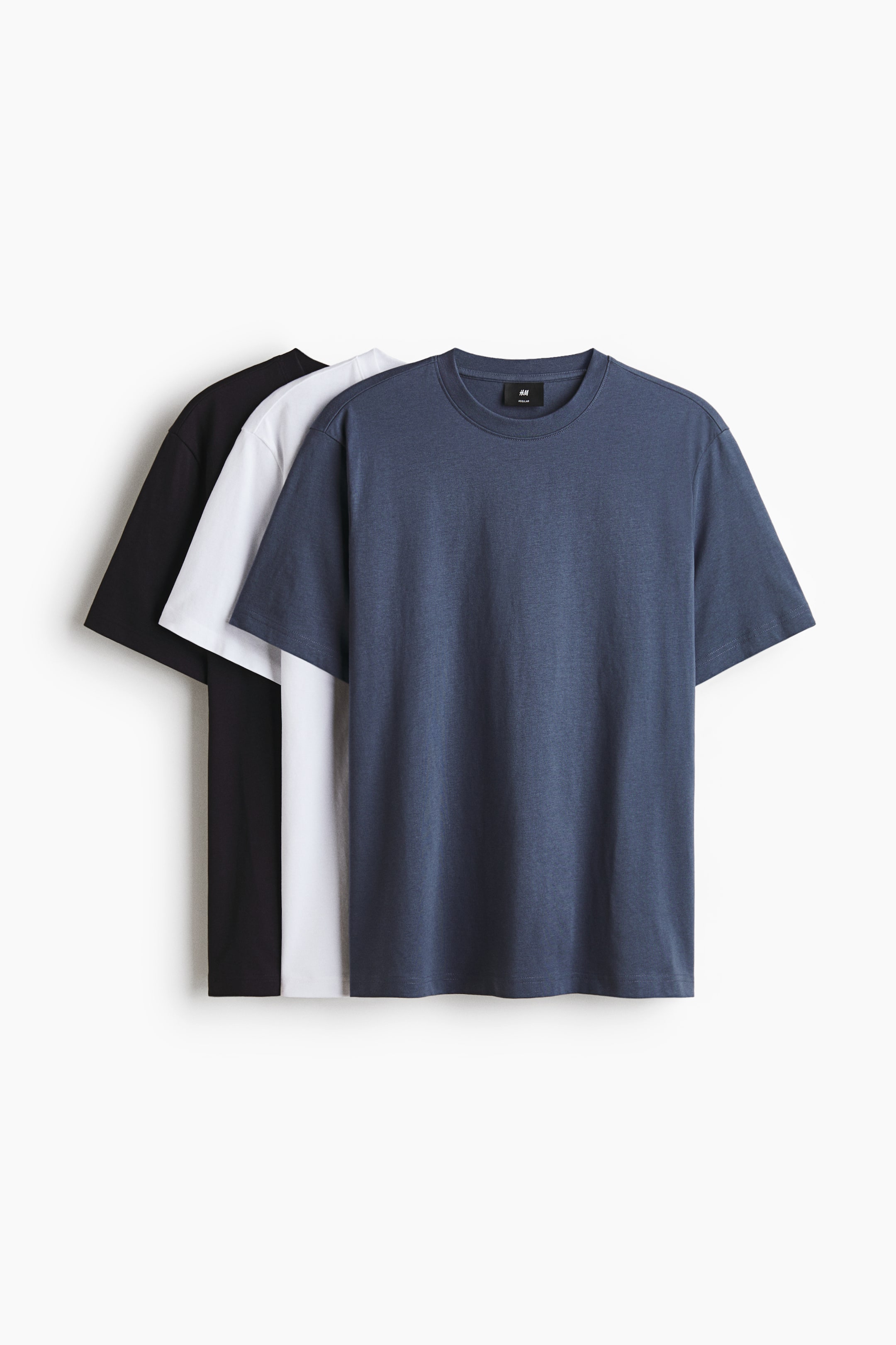 View larger image: Three t-shirts are layered, with a dark blue one in the foreground, a white one in the middle, and a black one behind, all facing front. Each t-shirt features a regular fit with a round, rib-trimmed neckline and a straight-cut hem, crafted from lightweight cotton jersey.
