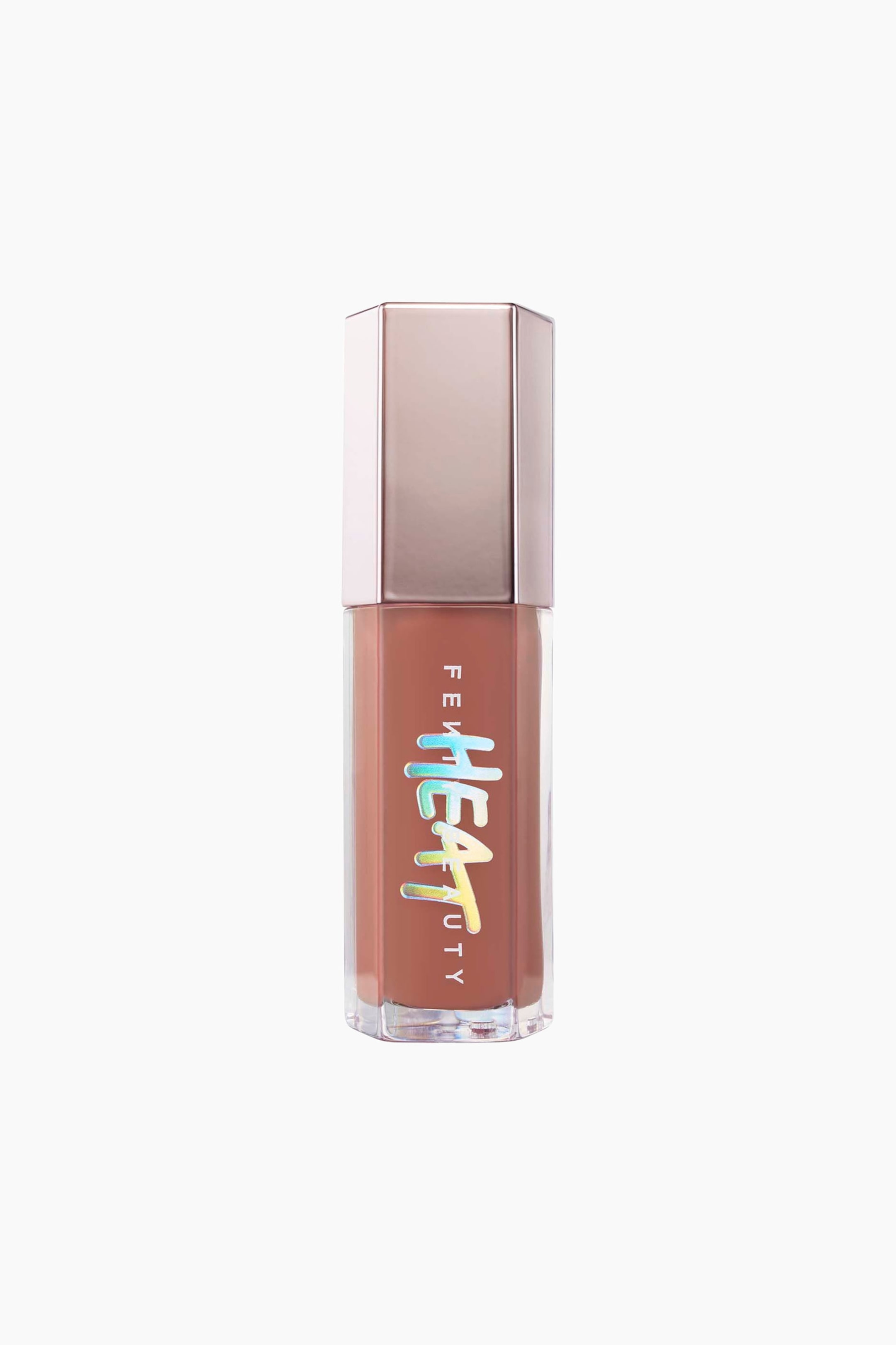 Visa större bild: Gloss Bomb Heat Universal Lip Luminizer + Plumper står upprätt och visar upp en genomskinlig sexkantig flaska fylld med ett varmt, brunaktigt nude-gloss. Den är toppad med ett reflekterande, metalliskt roséguldfärgat sexkantigt lock och visar en vertikal "FENTY BEAUTY"-logotyp med en holografisk "HEAT"-grafik i droppande stil ovanpå på framsidan.