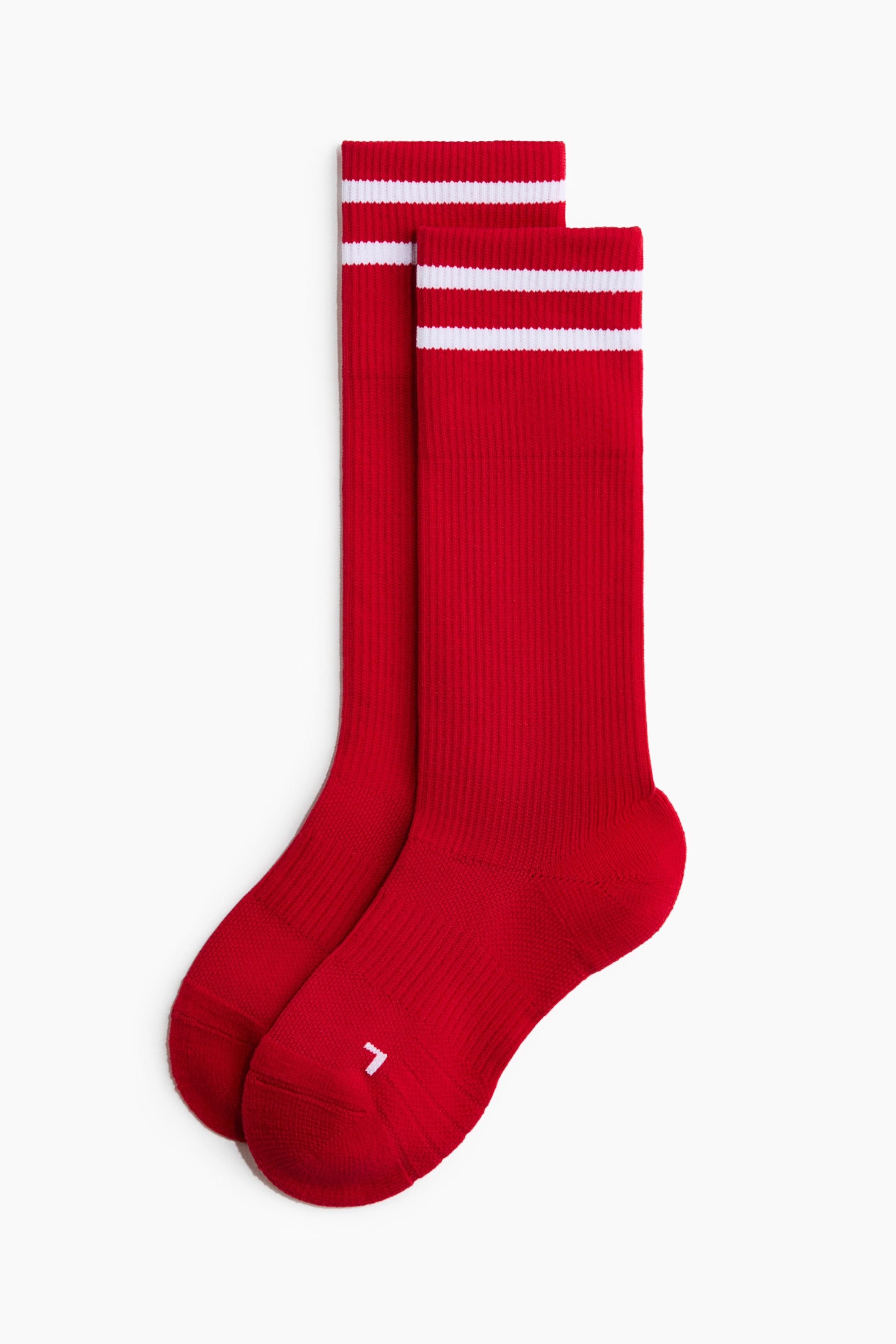 View larger image: Two red crew socks are displayed, showcasing ribbed shafts and two white stripes encircling the top cuffs. A small white arrow-like logo is visible on the instep of one sock.