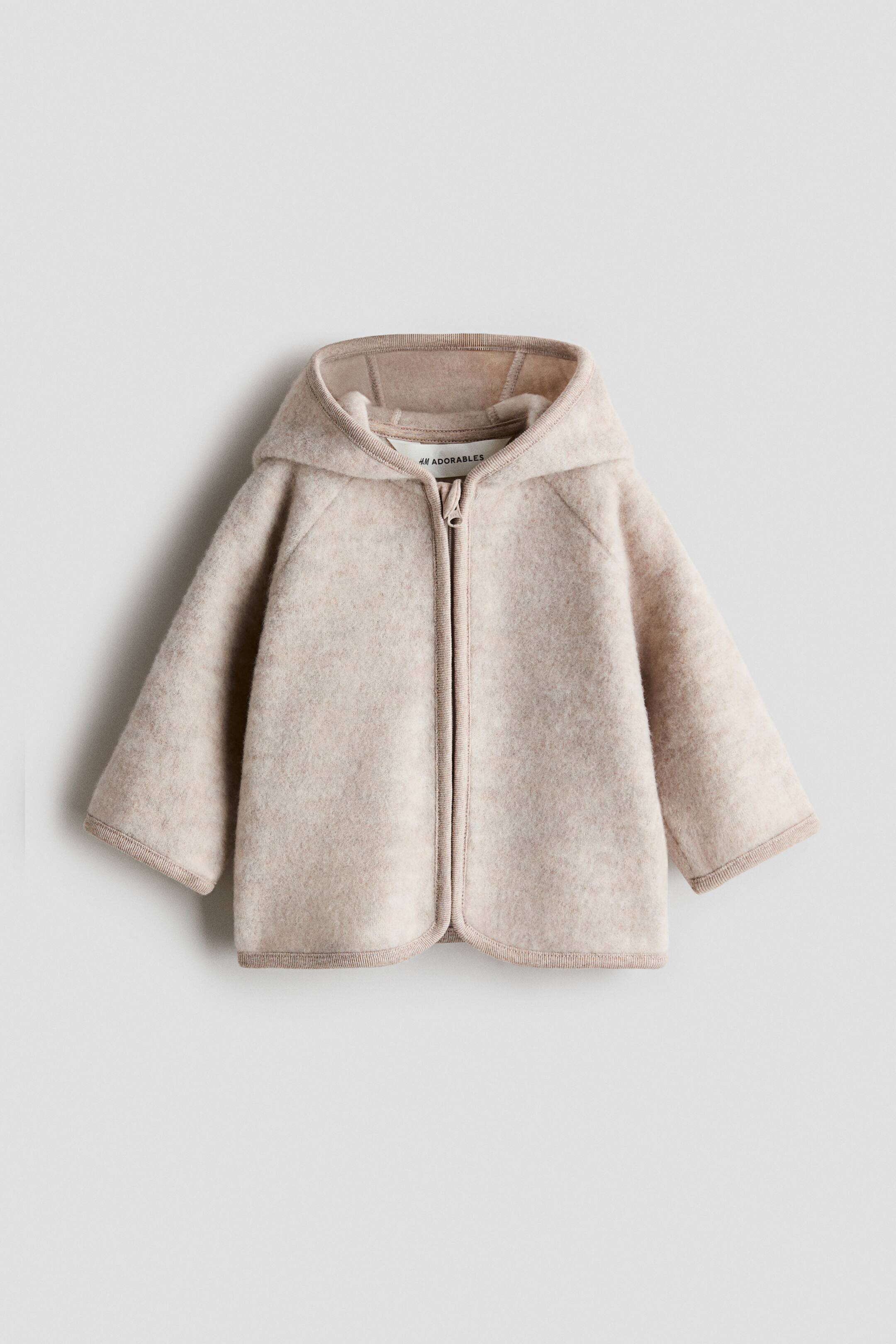 Agrandir l'image: Un cardigan en polaire beige clair H&M Adorables est présenté de face. Il est doté d'une capuche, de manches raglan longues, d'une fermeture éclair frontale dissimulée, et de bordures en jersey de coton le long du bord de la capuche, de l'ouverture frontale, de l'ourlet inférieur et des poignets.