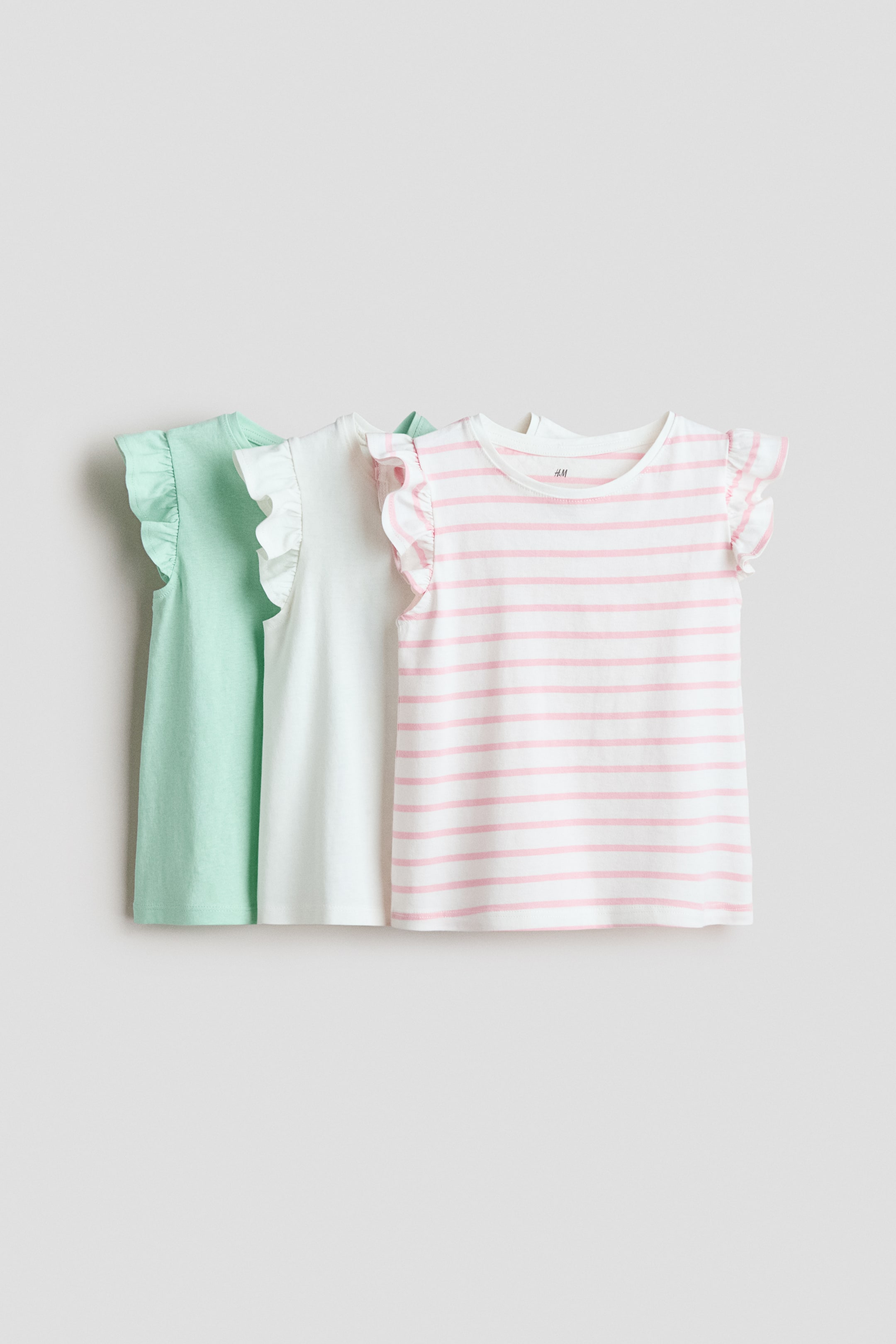 View larger image: Three soft cotton jersey tops are shown from the front, each with a round, ribbed neckline and flutter sleeves. Available in light green, white, and a white with pink horizontal stripe pattern.
