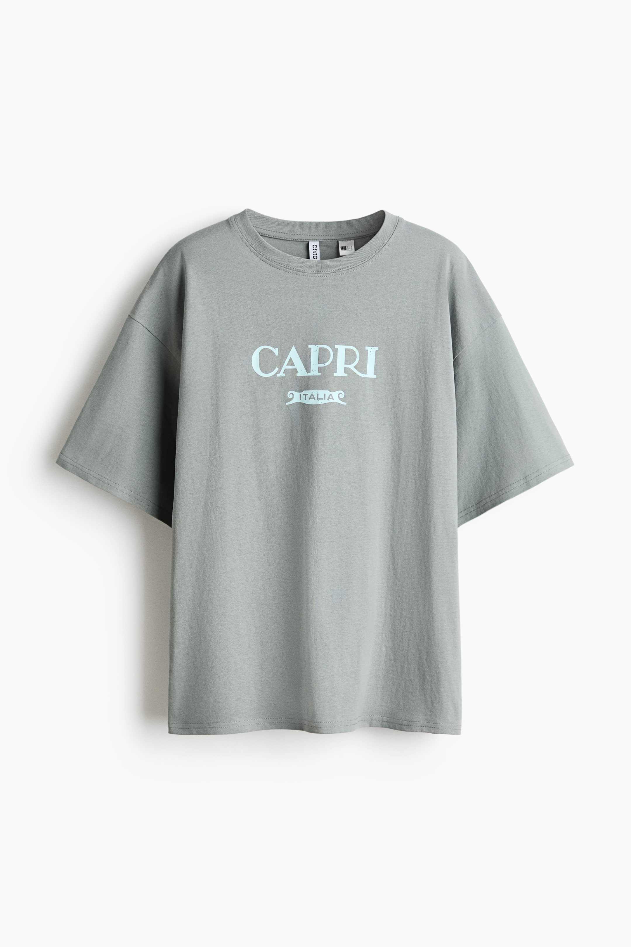 View larger image: An oversized sage green cotton jersey t-shirt is showcased from the front, featuring a light blue "CAPRI ITALIA" print across the chest. It includes a round, ribbed neckline and dropped shoulders.