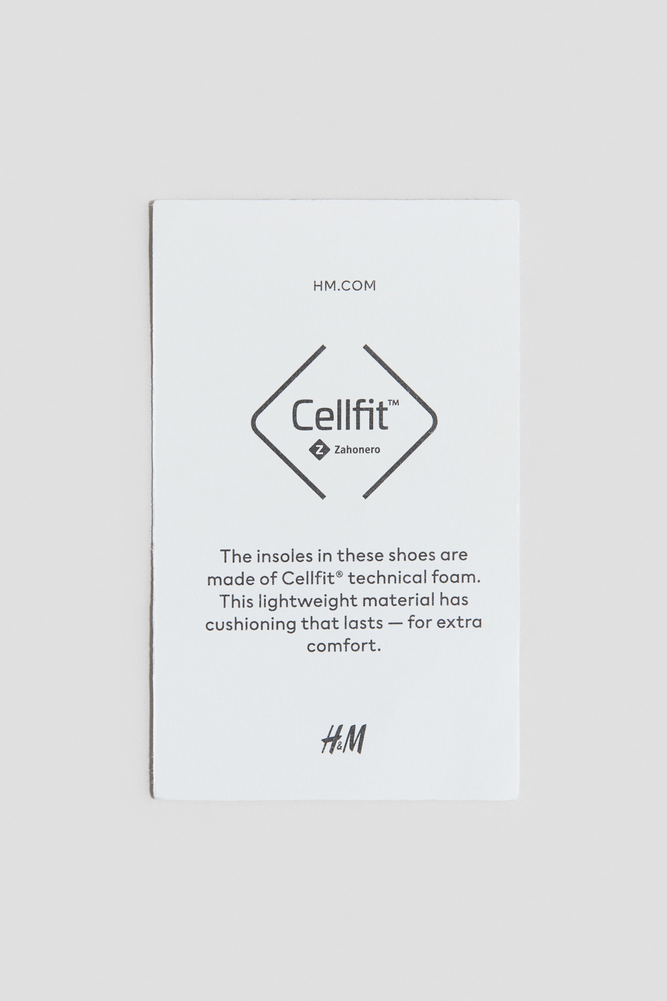 View larger image: A white rectangular product tag is facing FRONT, providing information for printed trainers. It is displaying black text including 'HM.COM', the 'Cellfit™' logo with 'Zahonero', and a description about Cellfit® technical foam insoles for shoes. The 'H&M' logo is visible at the bottom.