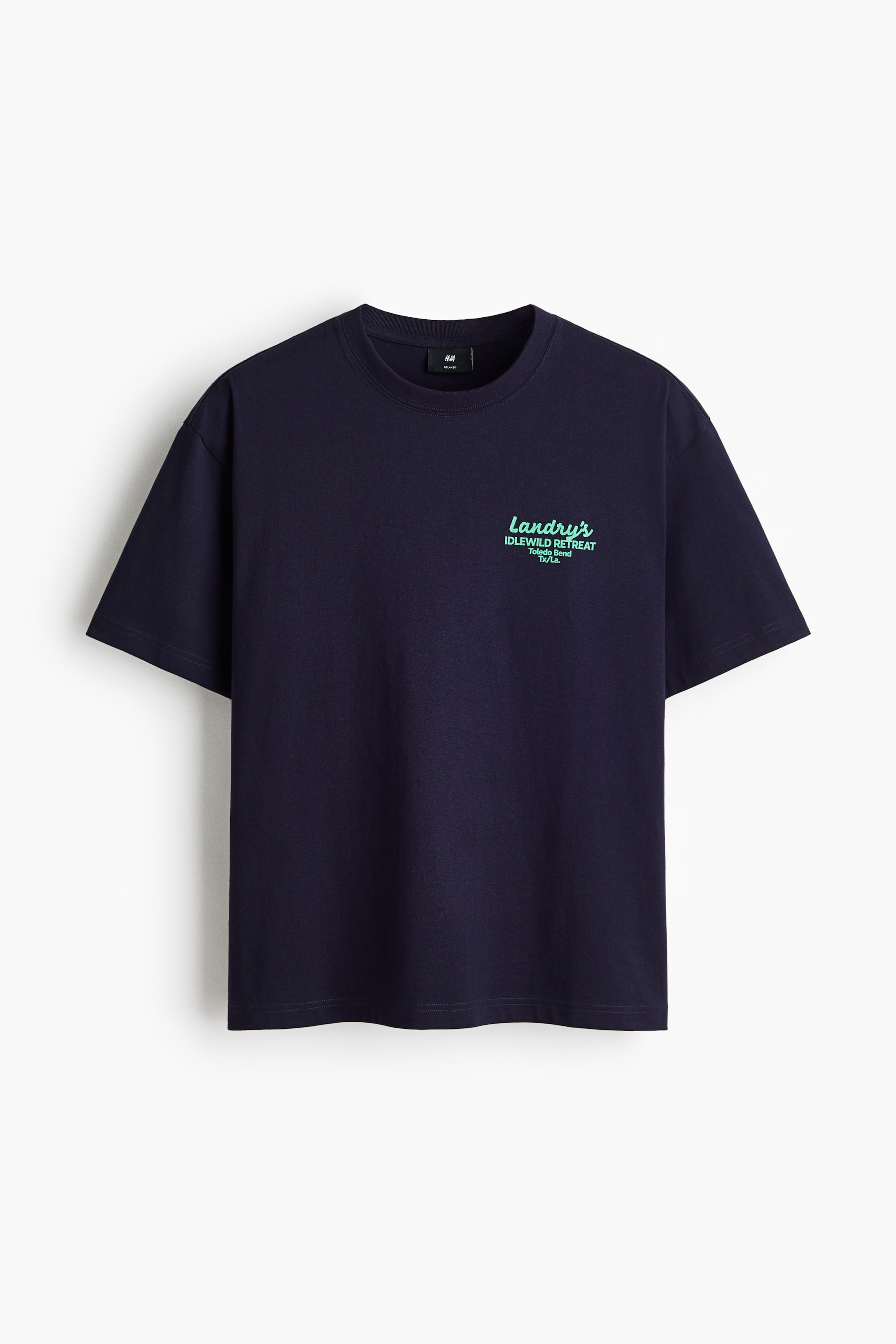 View larger image: The front view displays a dark blue midweight cotton jersey T-shirt. It features a round, rib-trimmed neckline and dropped shoulders. The left chest showcases a light greenish-blue print motif with the text "Landry's IDLEWILD RETREAT Toledo Bend TX/La." The T-shirt is completed with a straight-cut hem and is designed for a loose fit, offering a generous silhouette without being oversized.