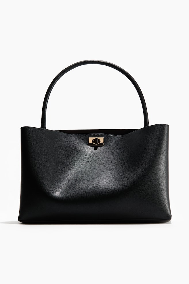 A black pebbled leather handbag is facing front, featuring a structured, rounded top handle. It is displaying a gold-toned turn-lock fastening at the centre top of its wide, slightly flared opening. - 1