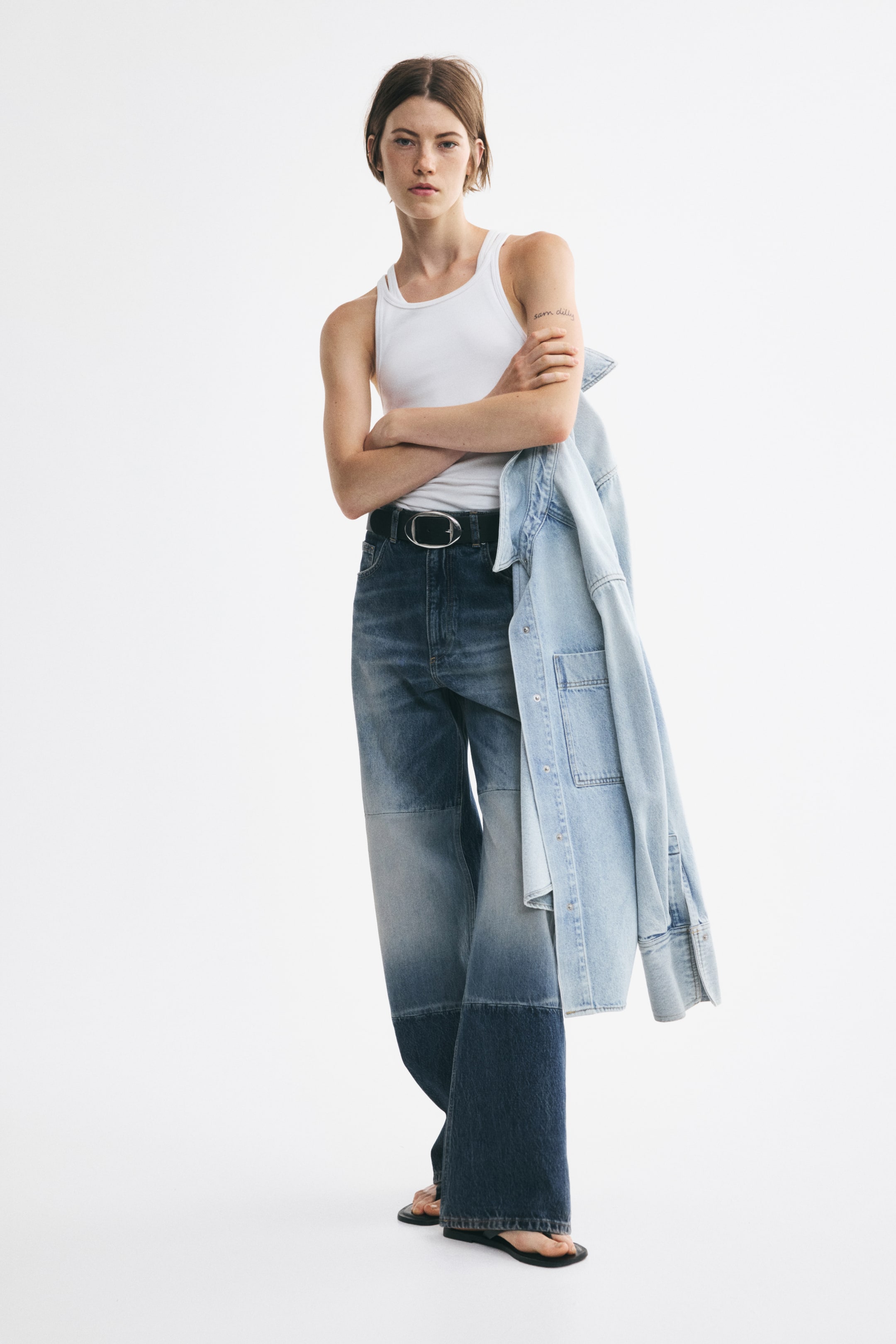 Grotere afbeelding bekijken: Deze vijfzakspatchworkjeans worden van voren gepresenteerd en zijn uitgevoerd met horizontale panelen in contrasterende blauwe denimwassingen. De jeans heeft een normale pasvorm aan de taille, is gestyled met een zwarte riem en valt los recht van de dijen tot aan de zoom, met minimale plooivorming.