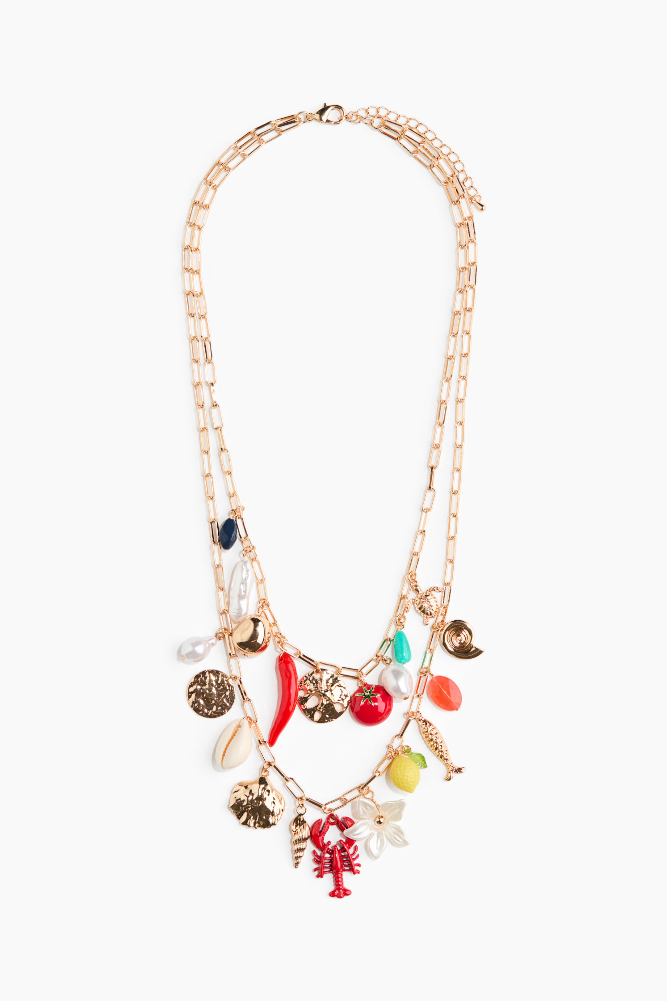 Agrandir l'image: Un collier à breloques superposées de ton doré est présenté en vue de face, avec deux chaînes à maillons de type trombone. Les deux chaînes sont ornées d'une variété de breloques colorées et de ton doré, incluant des fruits, des créatures marines, des coquillages, des motifs floraux, des disques texturés, et divers perles.