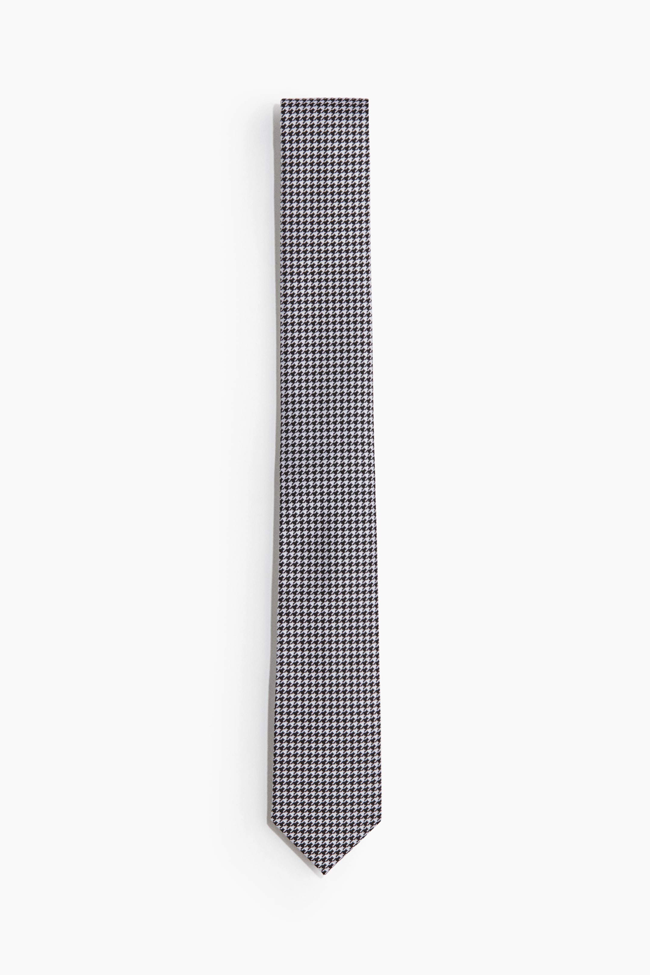Ampliar la imagen: Corbata clásica en tejido de punto, colocada de forma plana y orientada verticalmente, mostrando un patrón de pata de gallo en blanco y negro. Se estrecha hacia un extremo puntiagudo en la parte inferior.