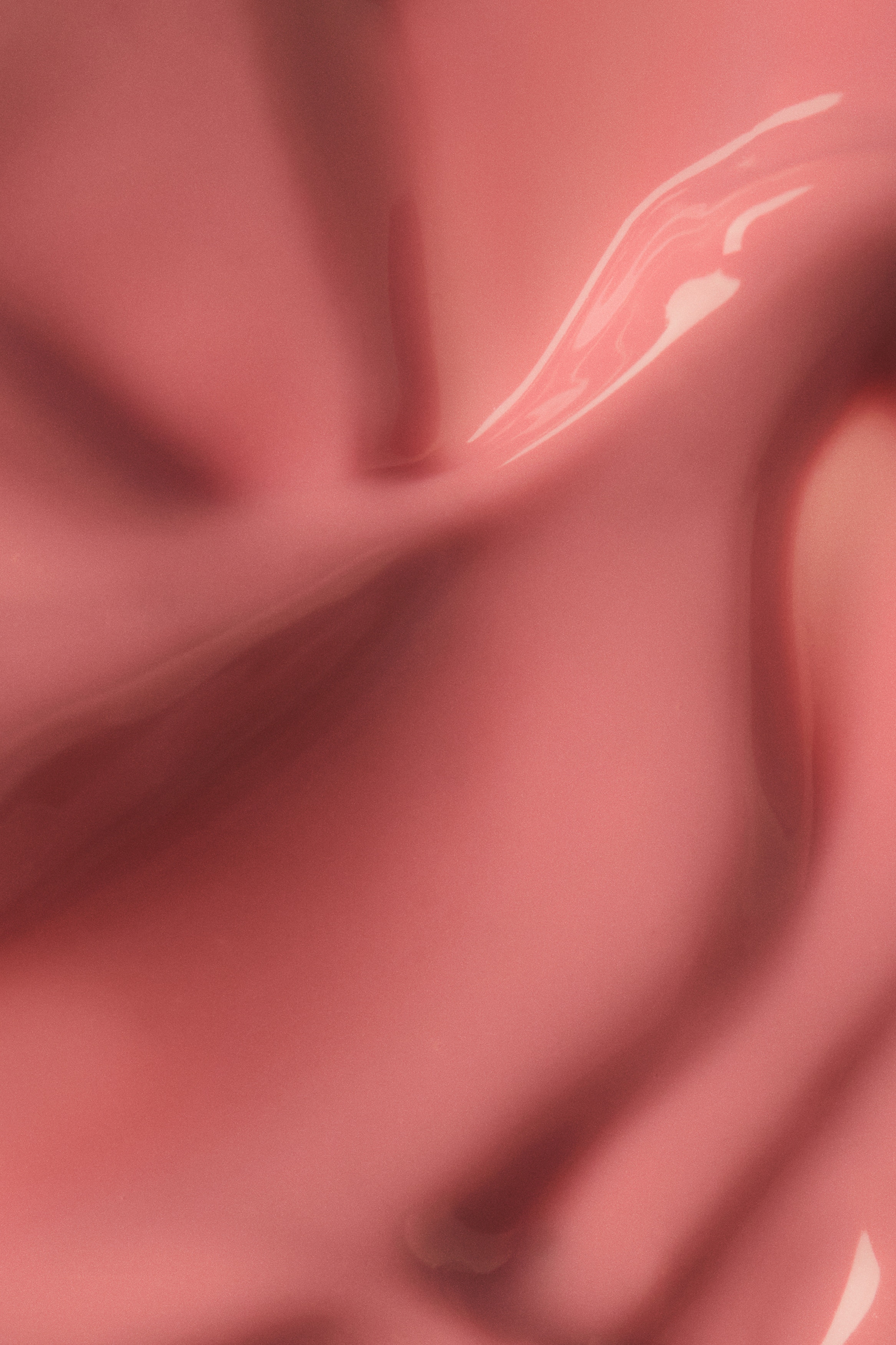 Um frasco de tint para os lÃ¡bios estÃ¡ de pÃ© na vertical, apresentando uma caixa exterior retangular transparente e fosca que envolve um tubo interior rosa-claro. O frasco Ã© encimado por uma tampa cilÃ­ndrica metÃ¡lica prateada, e texto vertical branco com a inscriÃ§Ã£o "GLOSS TINT" estÃ¡ exibido na frente do tubo interior.