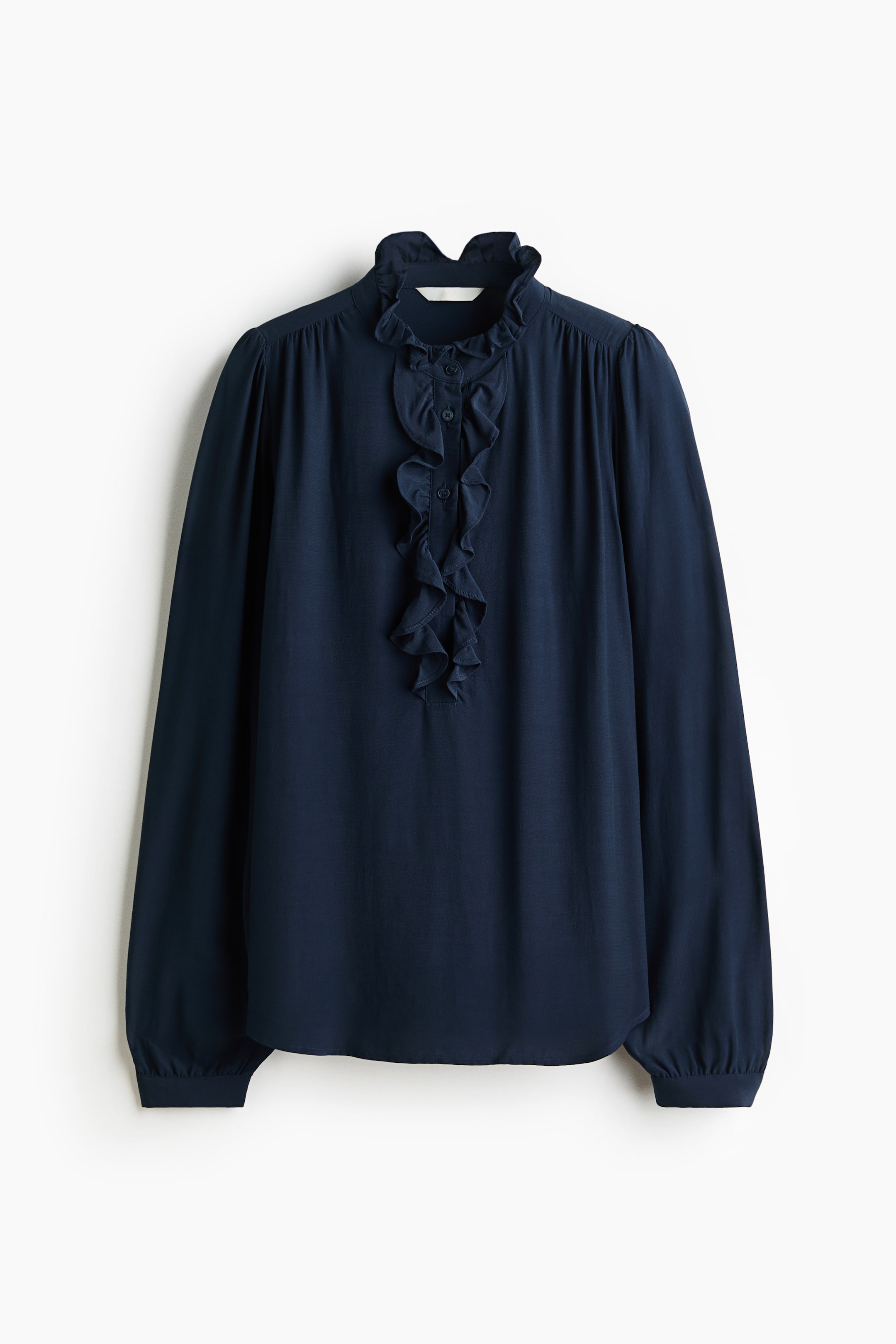 View larger image: A dark blue blouse is shown from the front, featuring a ruffled stand-up collar and a ruffled front placket with visible buttons. It is designed with long sleeves, gathered shoulders, and elasticated cuffs.