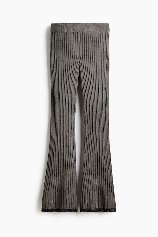 A pair of dark gray ribbed knit pants are presenting front-facing, featuring a wide elastic waistband and flaring legs with black scalloped lace trim detailing the hem. - 1