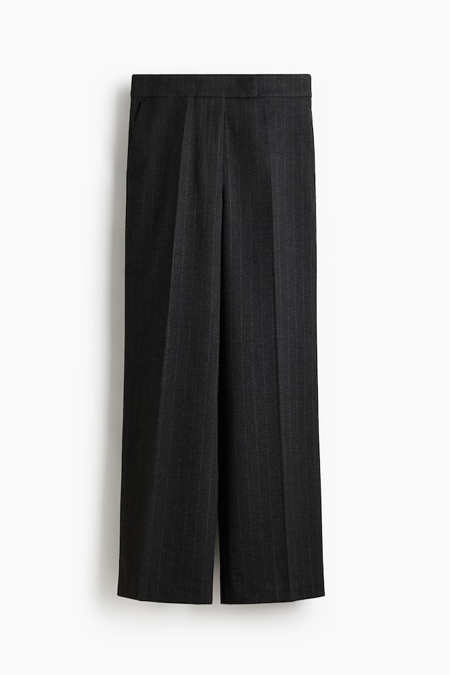 Tailored trousers in a dark, pinstriped woven fabric are being presented from the front. They are featuring an extended waistband, diagonal side pockets, and straight legs with creases running down the front. - 1