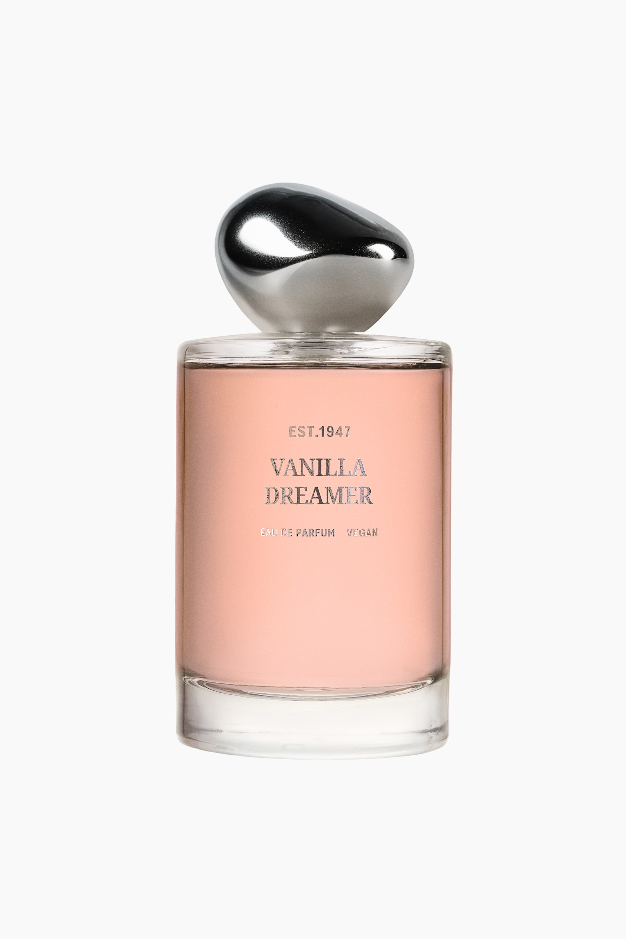 Visualizza immagine più grande: Vanilla Dreamer EdP si presenta in un flacone di vetro trasparente, rettangolare, riempito di un liquido rosa pesca chiaro. Un tappo lucido color argento, dalla forma organica, completa il flacone, mentre sul fronte è riportata la scritta argento "EST.1947 VANILLA DREAMER EAU DE PARFUM VEGAN".
