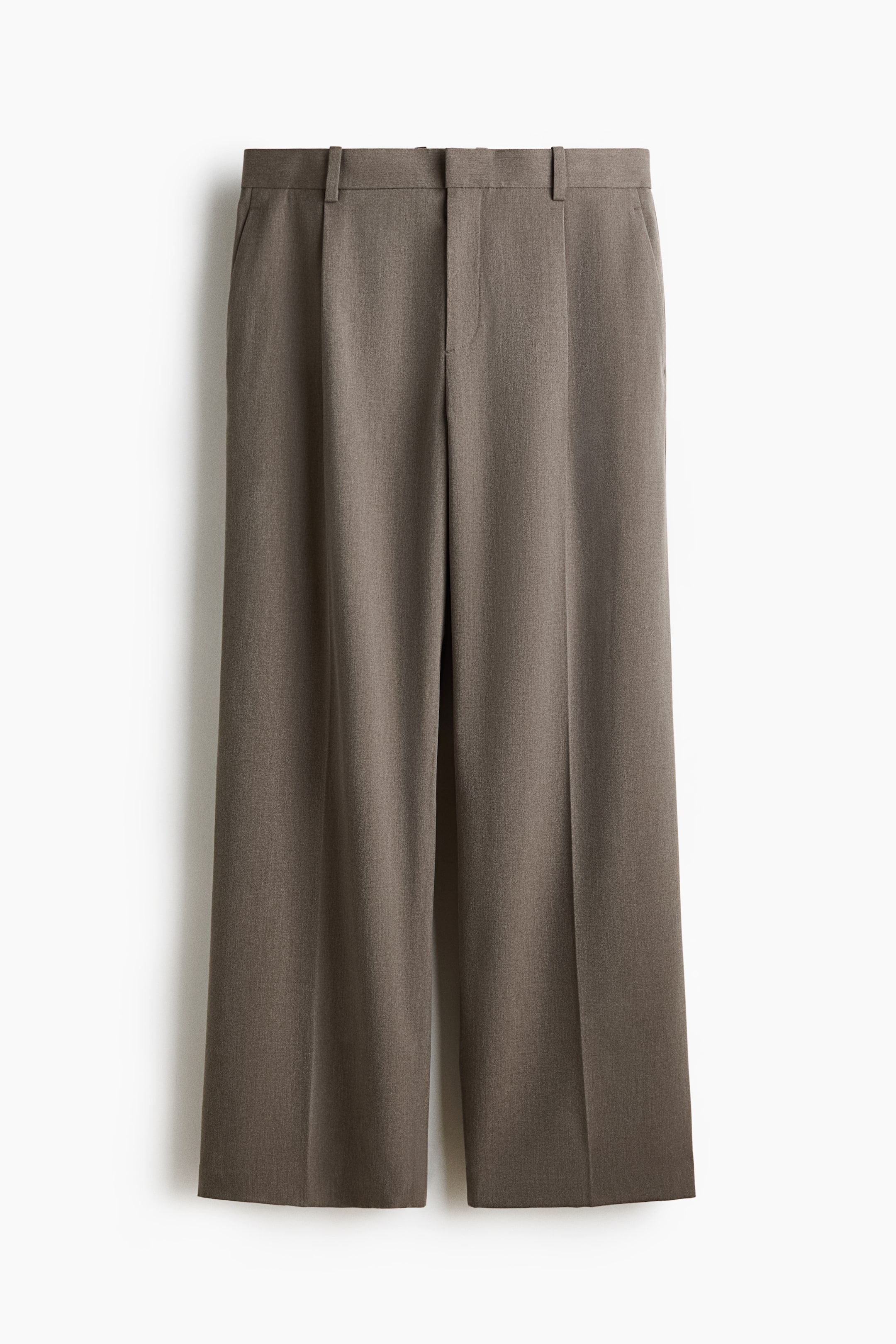 Voir une image plus grande: Pantalons en sergé brun sur mesure présentant leur devant, avec une ceinture à passants, des poches latérales diagonales et des jambes larges avec des plis avant marqués, créant une silhouette ample.