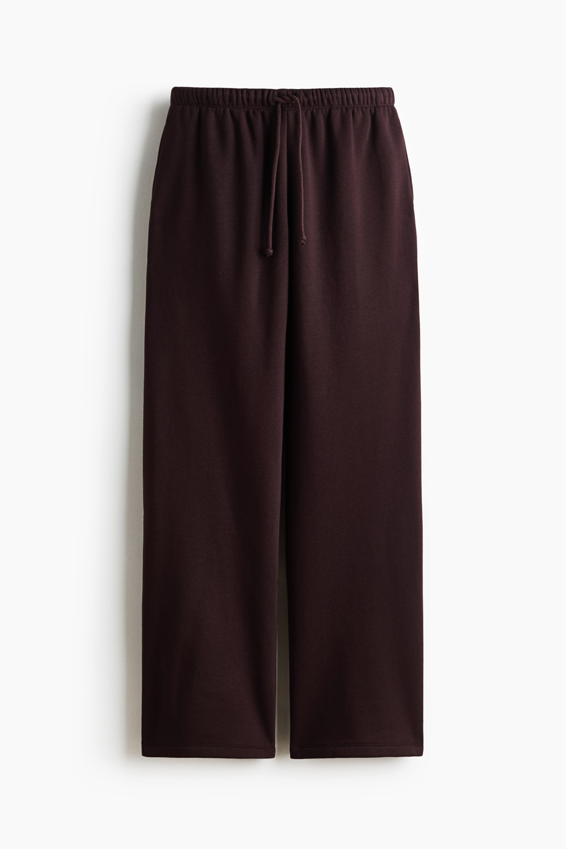 View larger image: Loose-fit joggers in dark brown sweatshirt fabric are showcased from the front, featuring an elasticated drawstring waist and wide legs.