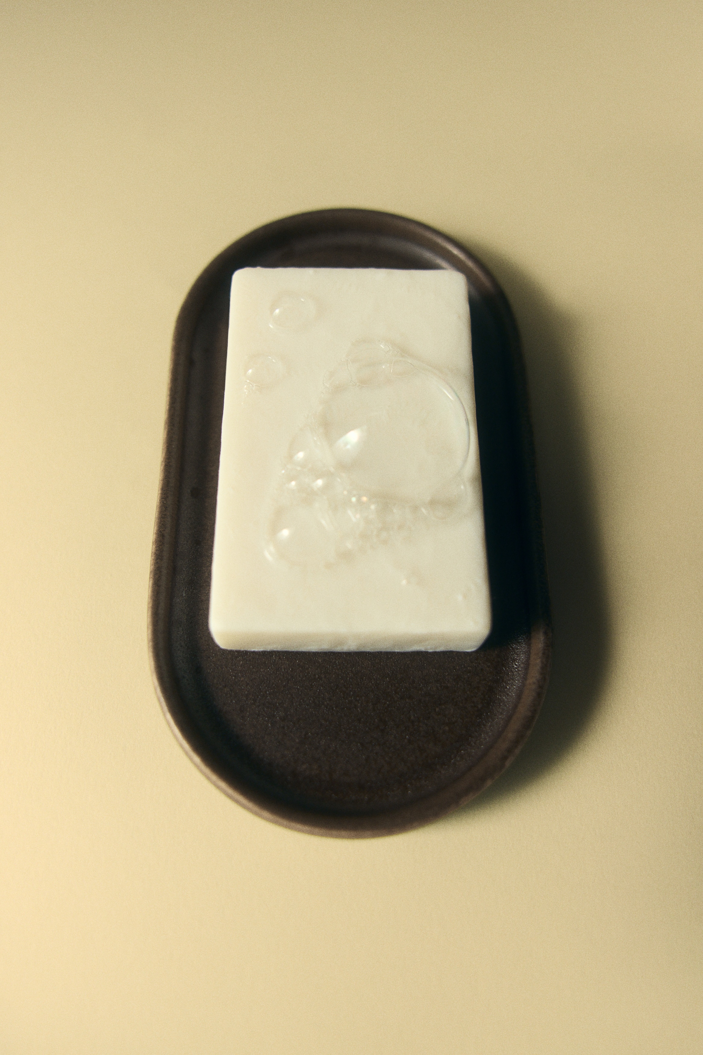 An oval dark brown glazed stoneware tray features a low rim, positioned facing forward at a slight angle.
