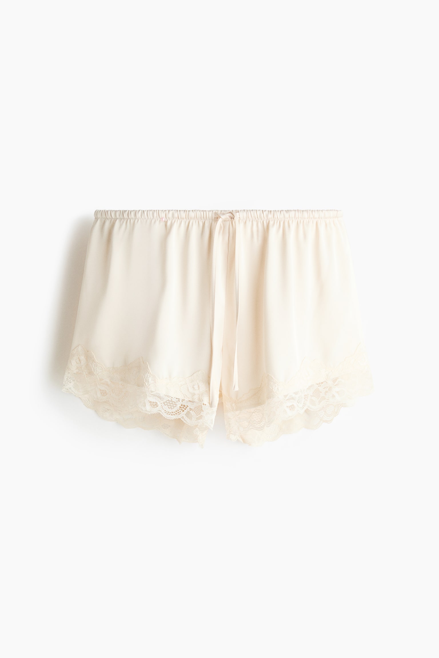 Quần short màu kem nhạt, làm từ satin mềm mại, có thể nhìn thấy từ phía trước, nổi bật với cạp chun co giãn, dây rút và gấu quần viền ren. - 1