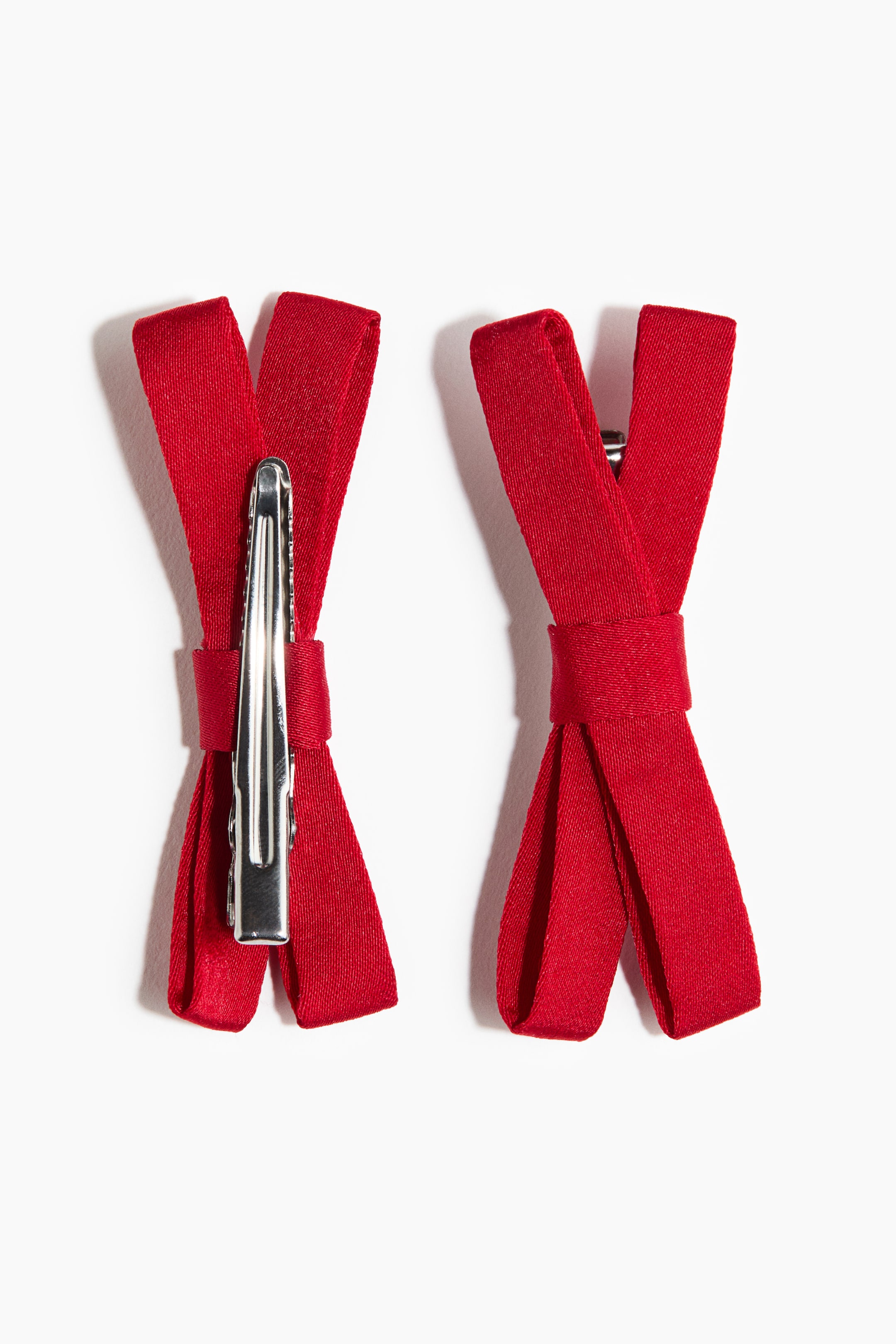 View larger image: Two metal hair clips are presenting front-facing, each featuring a narrow, red fabric bow wrapped around a silver-toned pinch clip.