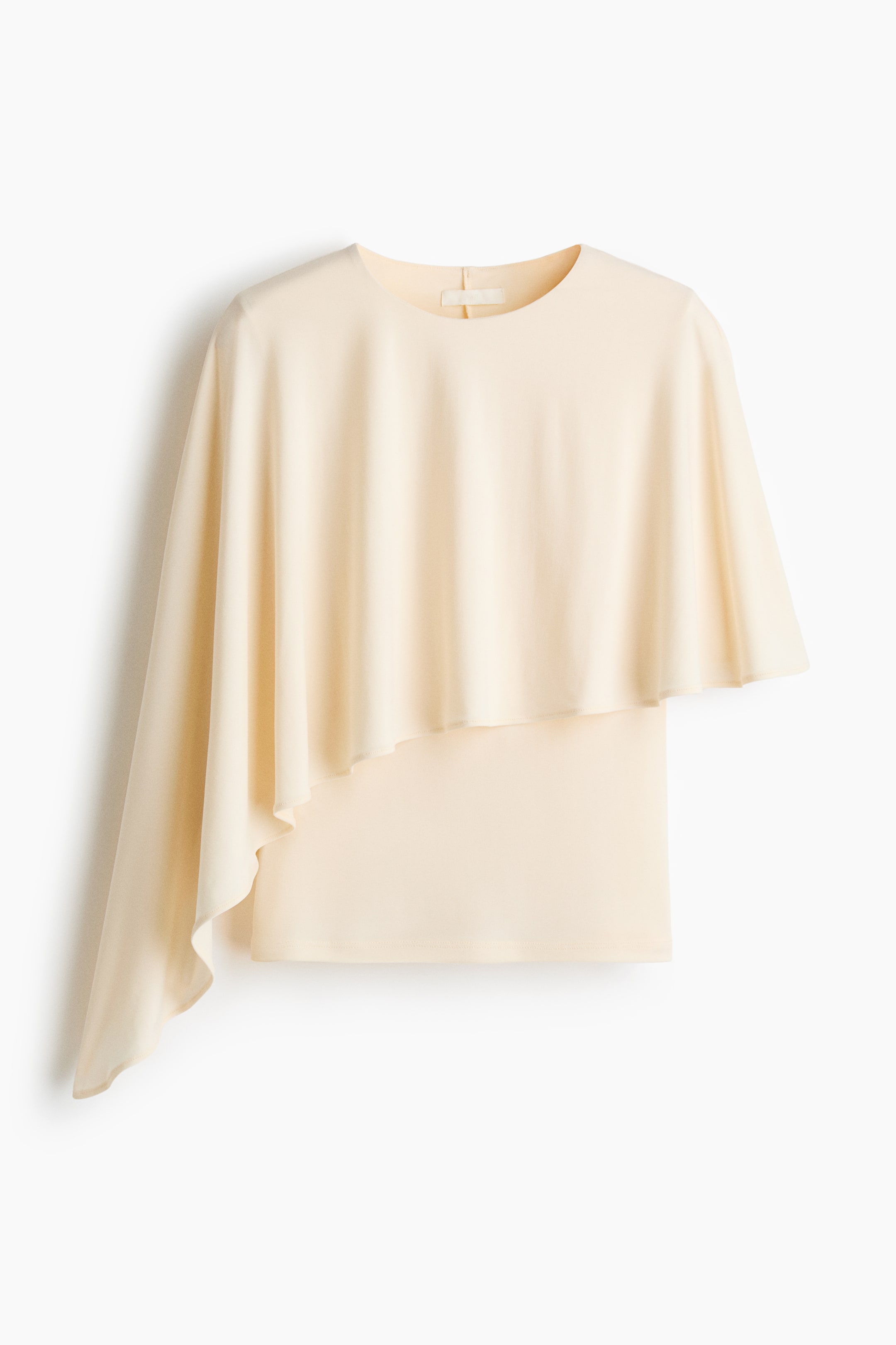 View larger image: The FRONT of a cream-coloured soft jersey top features a round neckline. An asymmetric, cape-like layer gracefully drapes over the top, extending longer on the left side.