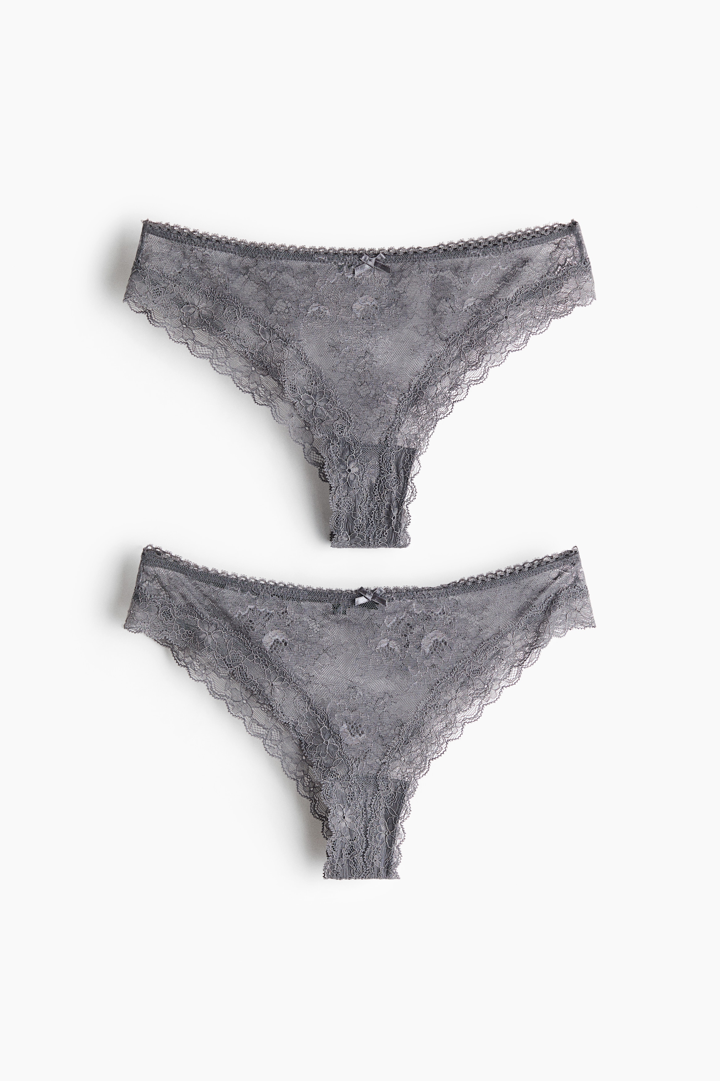 Model ma na sobie szare koronkowe figi z Årednim stanem, falistymi brzegami i maÅÄ kokardkÄ z przodu. Figi sÄ zestawione z dopasowanym szarym koronkowym bralette.