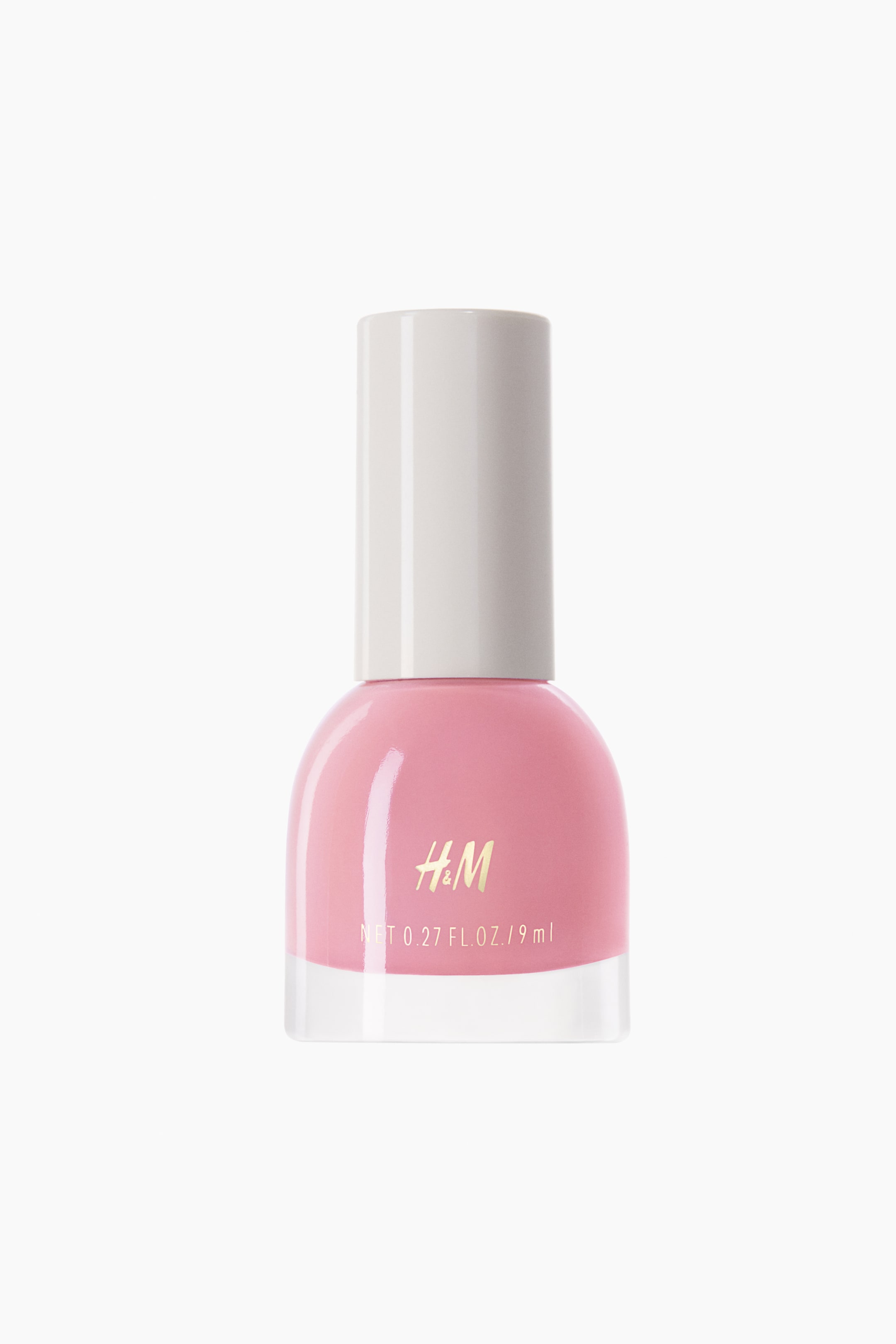 View larger image: A light pink nail polish bottle stands upright, facing forward. The clear glass base holds the pink polish, while an off-white cylindrical cap covers the top. Gold "H&M" lettering and volume details are visible on the front of the bottle.