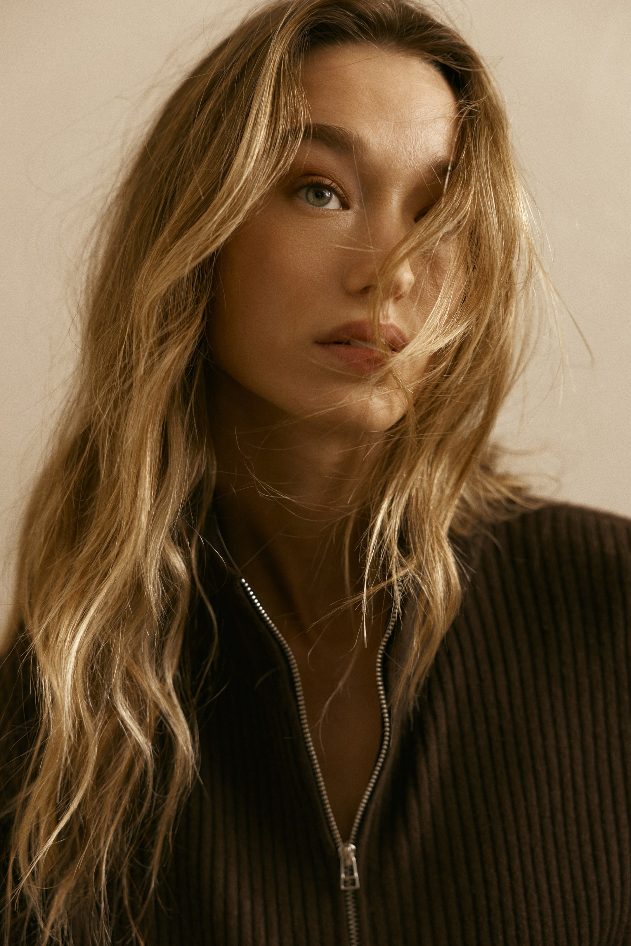 拡大画像を表示: 濃い茶色のリブ編みトップは、フロントに部分的に開いたシルバートーンのジッパーが特徴です。