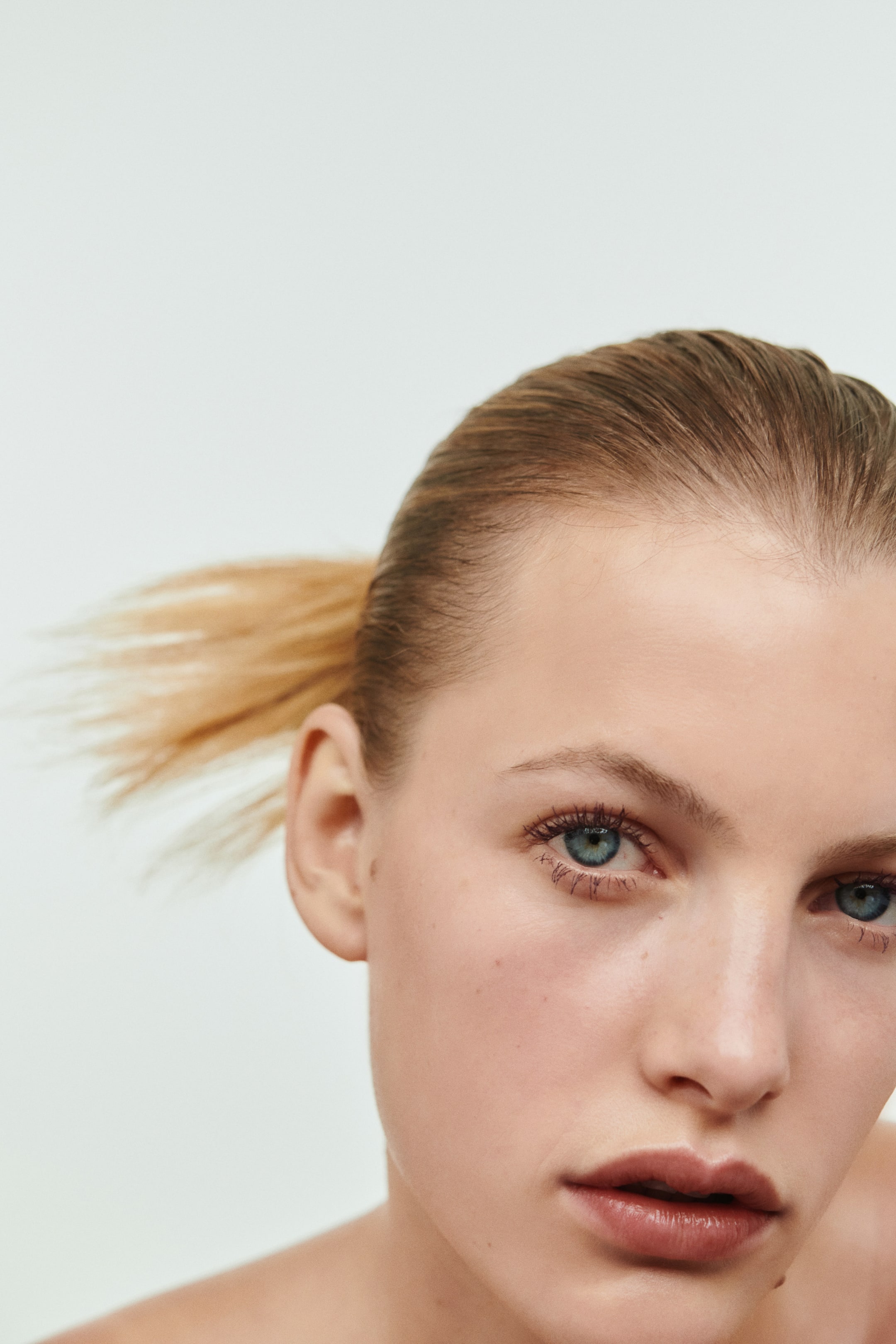 Agrandir l'image: Le mannequin porte un mascara à fort volume sur les cils, offrant un volume visible et une séparation nette. La formule sombre et pigmentée apporte une couleur intense aux cils supérieurs et inférieurs.