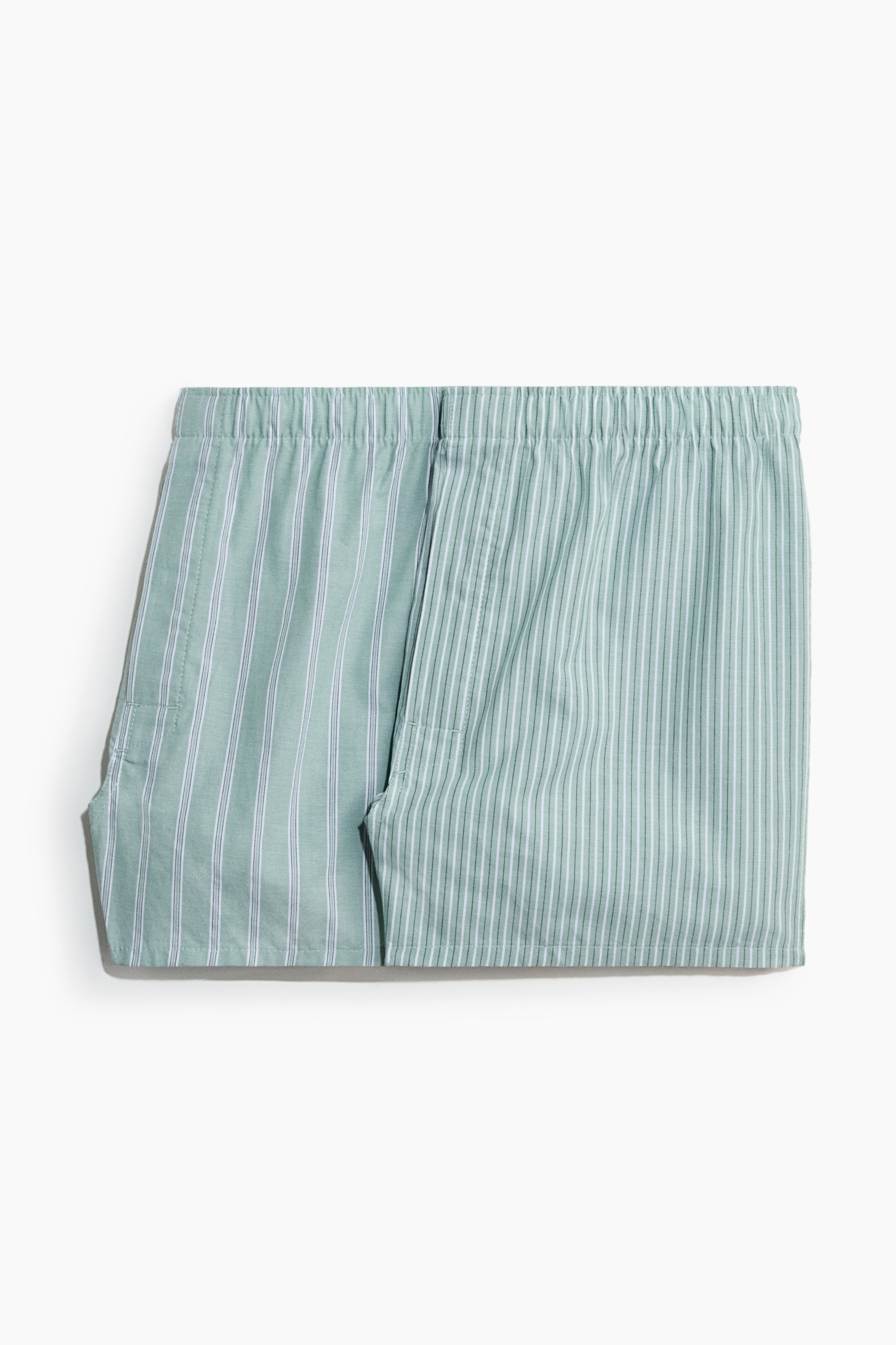 Visa större bild: Boxershorts visar ett mjukt vävt tyg och en elastisk midja, presenterad platt vikt från framsidan. De har en ljusgrön färg med vertikala vita ränder, medellånga ben och en knappgylf.