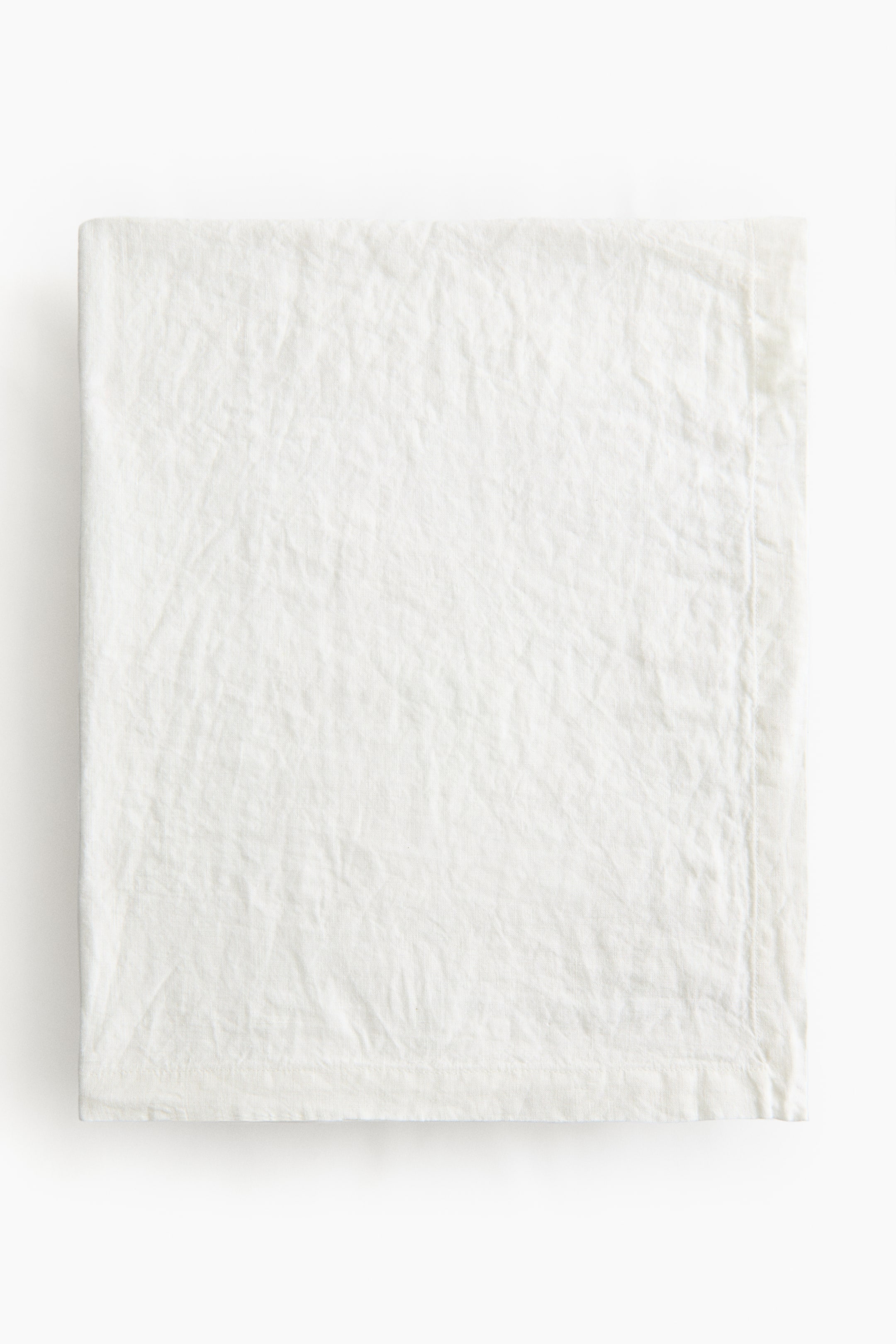 Agrandir l'image: La nappe présente un tissu blanc en tissage lin, plié. Elle est dotée d'un ourlet replié de 2,5 cm le long de ses bords.