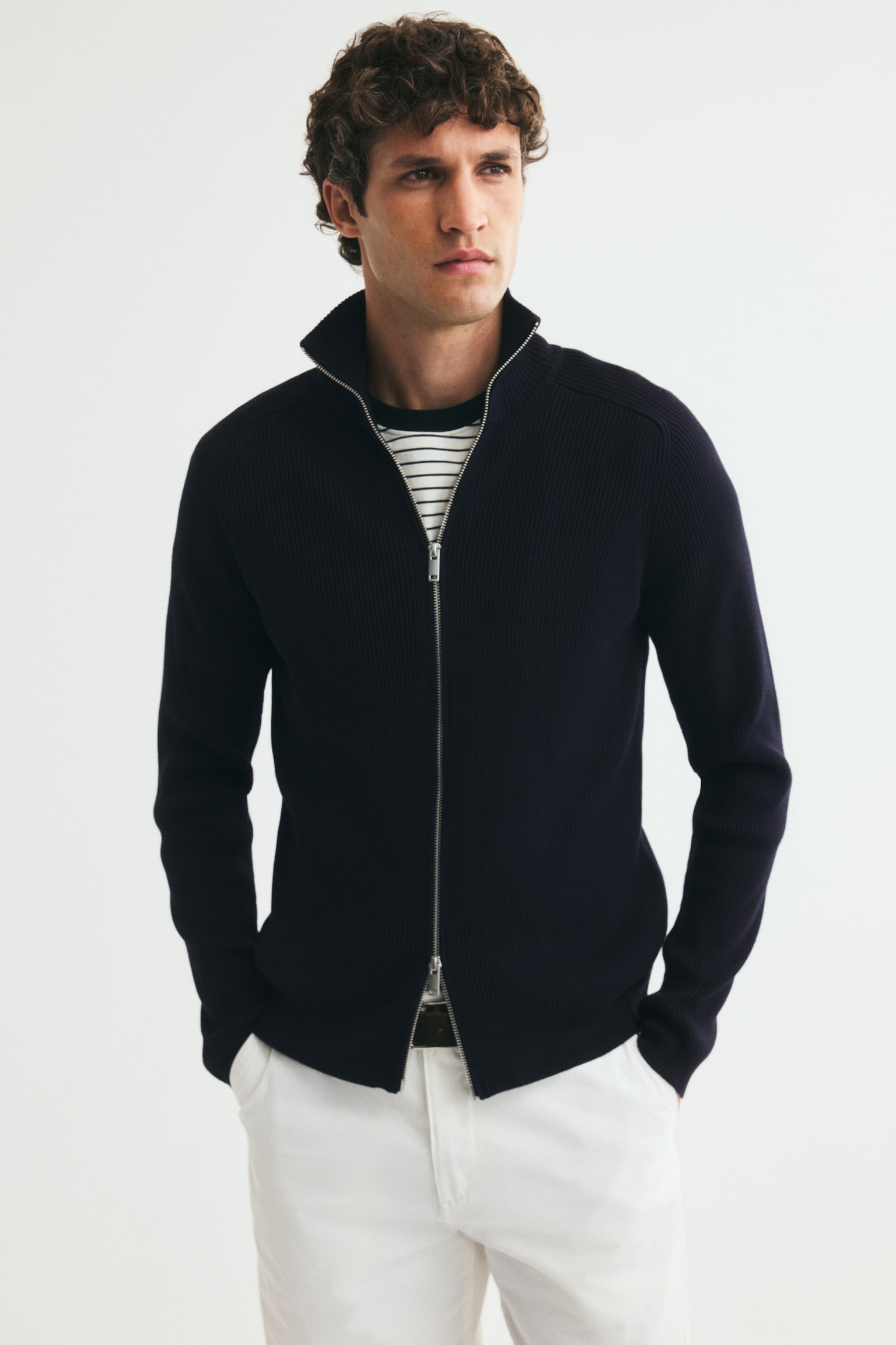 A navy blue ribbed knit full-zip sweater is presenting its front, featuring a stand-up collar, long sleeves with ribbed cuffs, a ribbed hem, and a silver-toned zipper. - 1