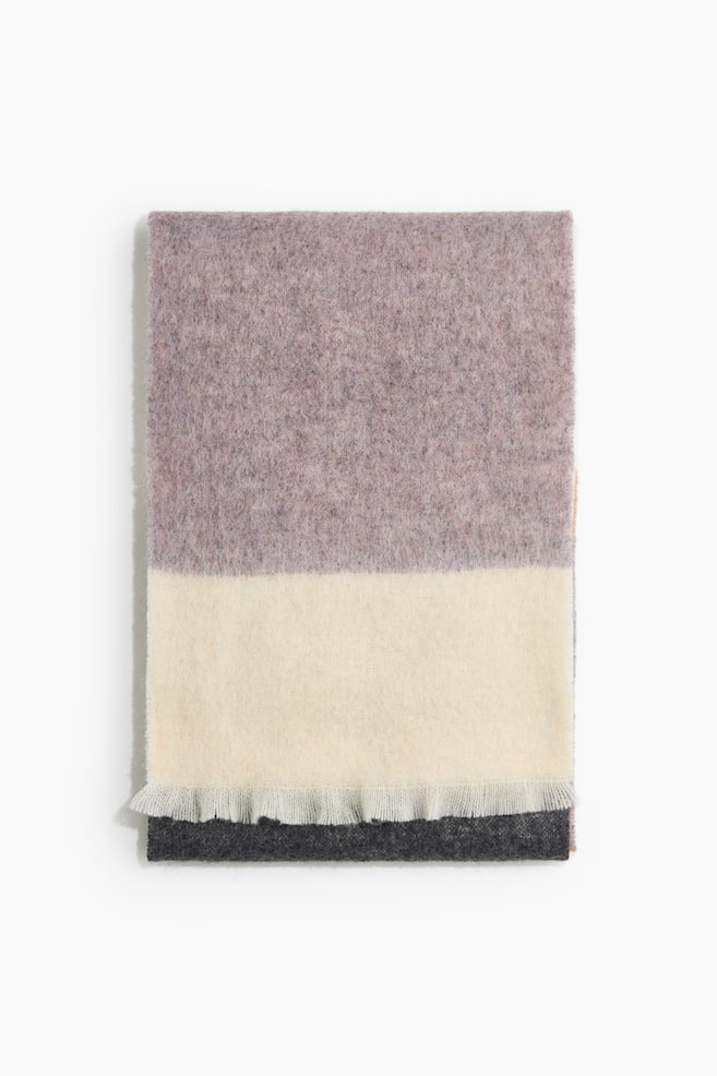 Una bufanda ancha de punto suave y ligeramente cepillado presenta paneles horizontales de bloques de color en morado empolvado, crema y gris carbÃ³n. La bufanda se muestra doblada en plano desde el frente, destacando su textura afelpada y los bordes deshilachados cortos a lo largo del bajo. - 1