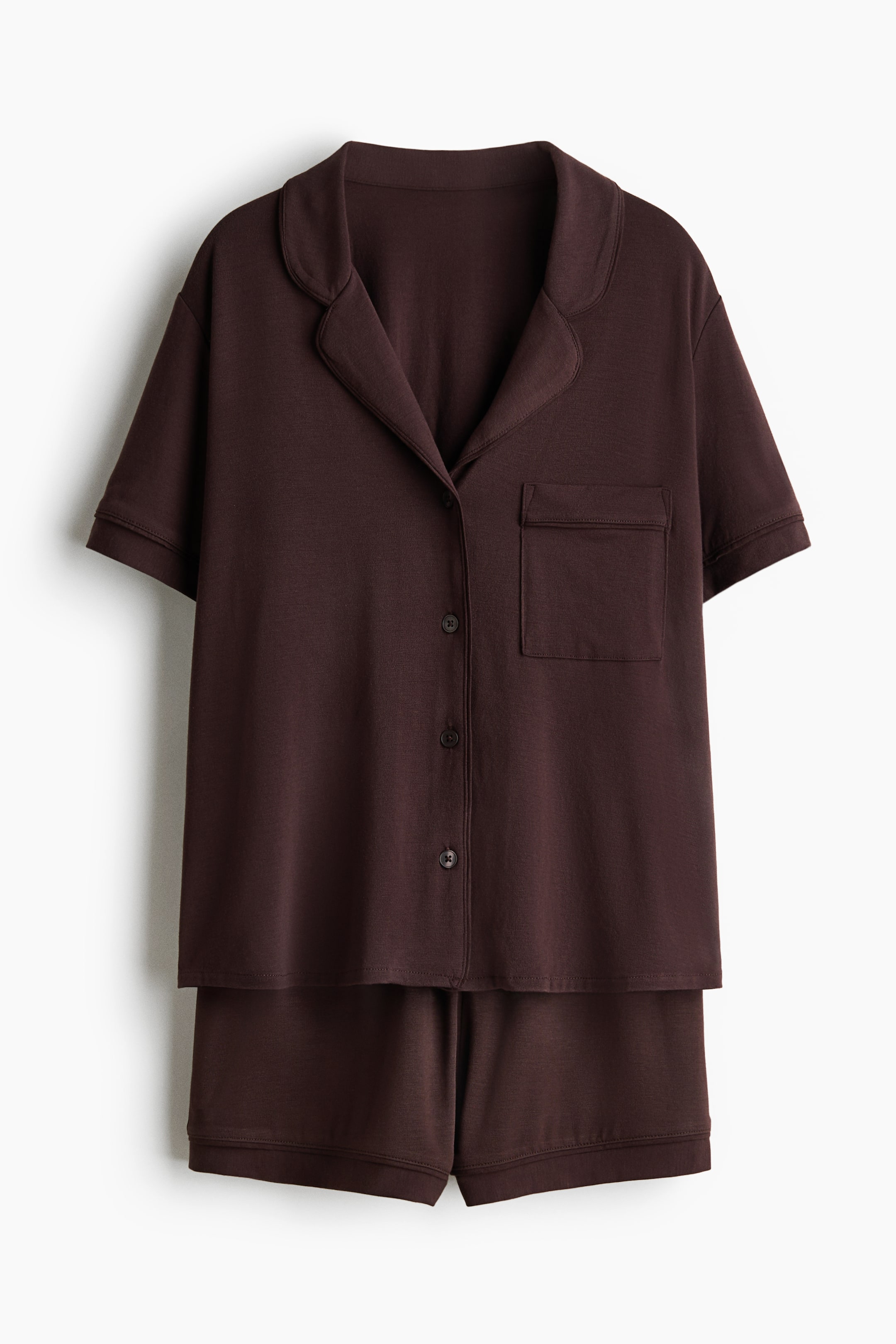 View larger image: A dark brown pyjama set is showcased front-facing, featuring a short-sleeved shirt with a resort collar, a front button-down closure, gently dropped shoulders, and a left chest patch pocket. The matching shorts present a relaxed fit with a covered elasticated waist.