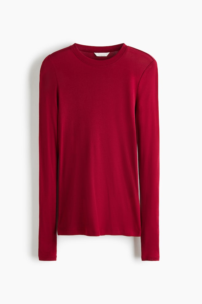 Un haut ajusté en jersey de coton pima rouge profond est suspendu de face, présentant un col rond et des manches extra-longues. - 1