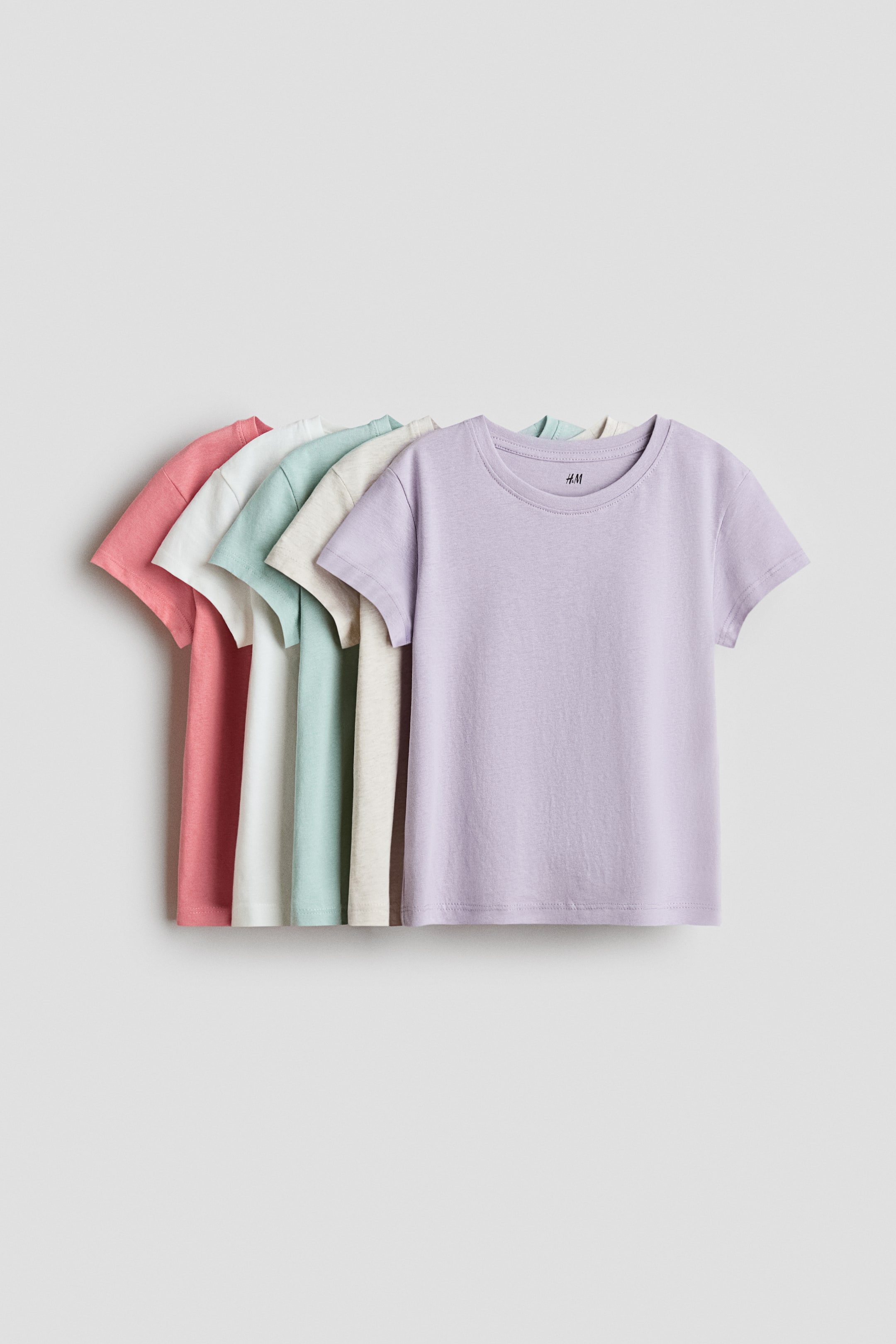 View larger image: Five jersey T-shirts present their fronts, layered in pastel colours. Each T-shirt features a round, rib-trimmed neckline, gently dropped shoulders and short sleeves.