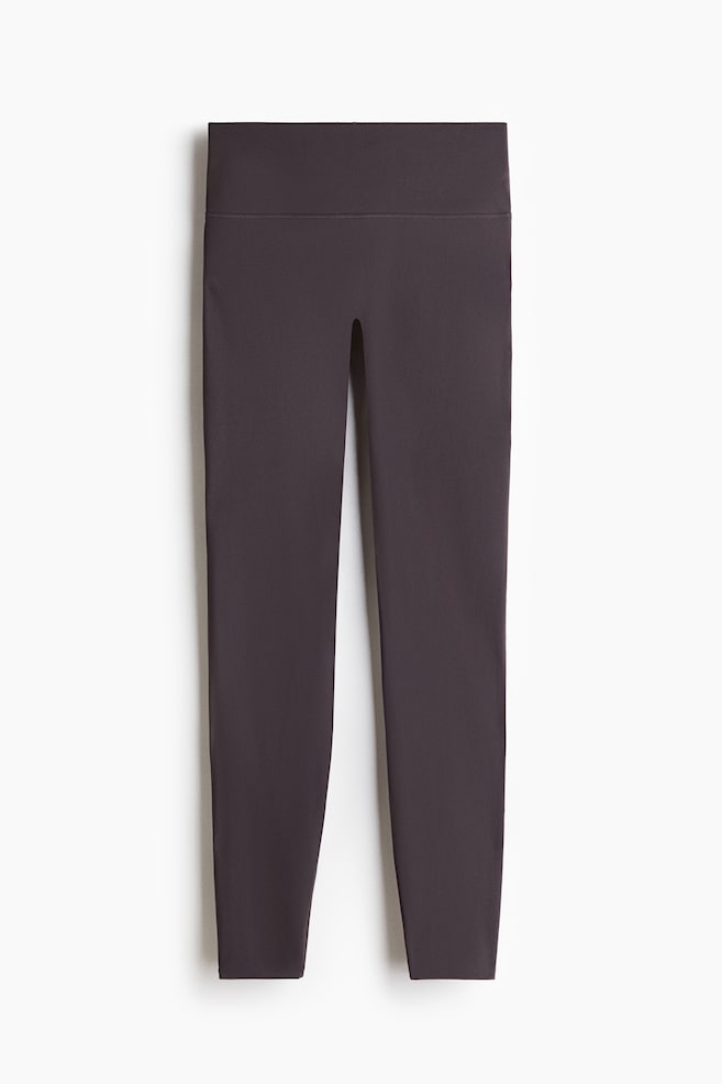 Sports leggings are showcased in a charcoal grey hue, positioned facing forward. They feature a wide, high-rise waistband and a sleek, close-fitting silhouette with clean, finished hems. - 1